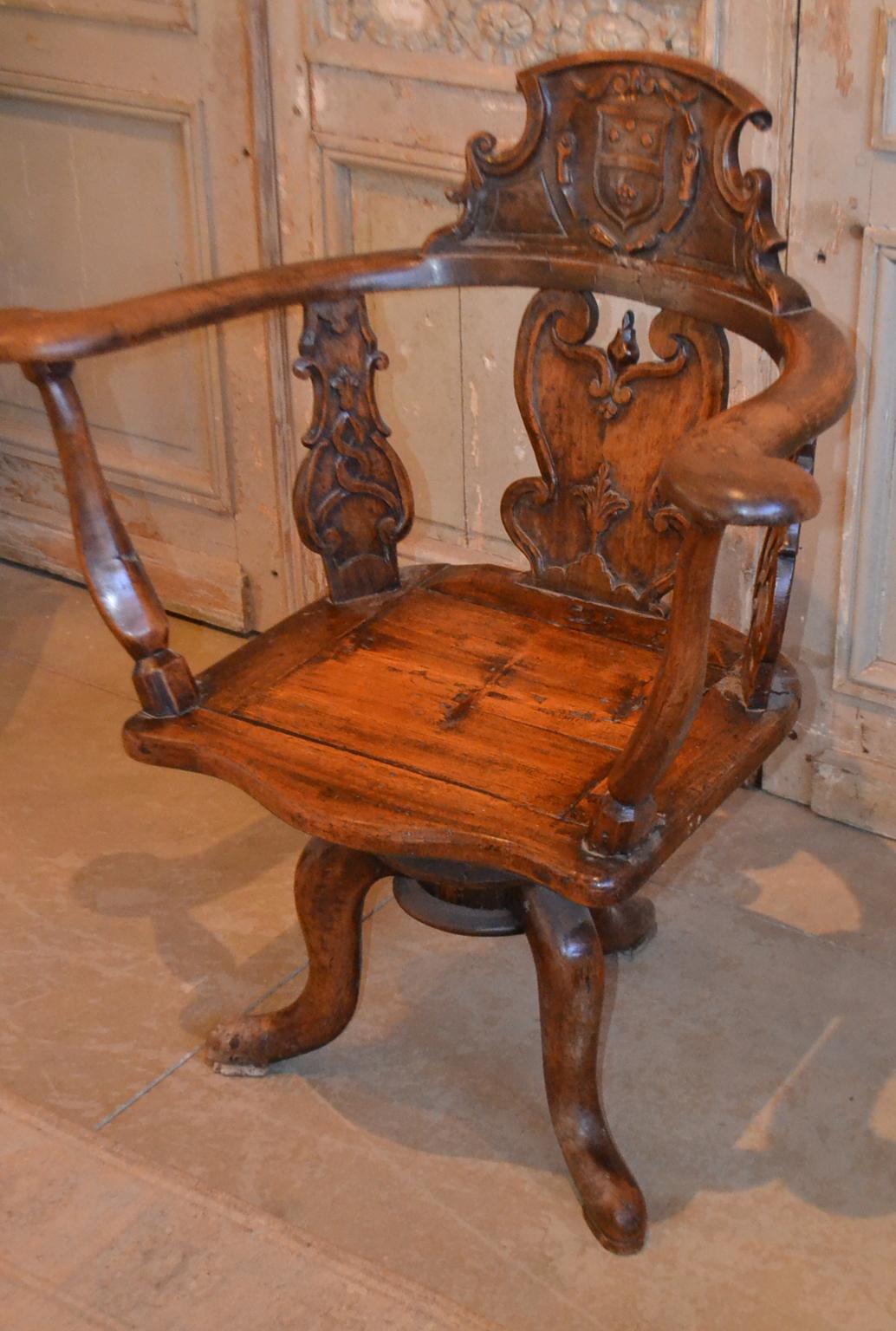 19th century Swiss hand carved wood chair with central cartouche and what appears to be a coat of arms, a carved molding of floral and scroll motifs for the vertical rails, rounded arm rests on octagonal carved cylinder supports, flat seat resting