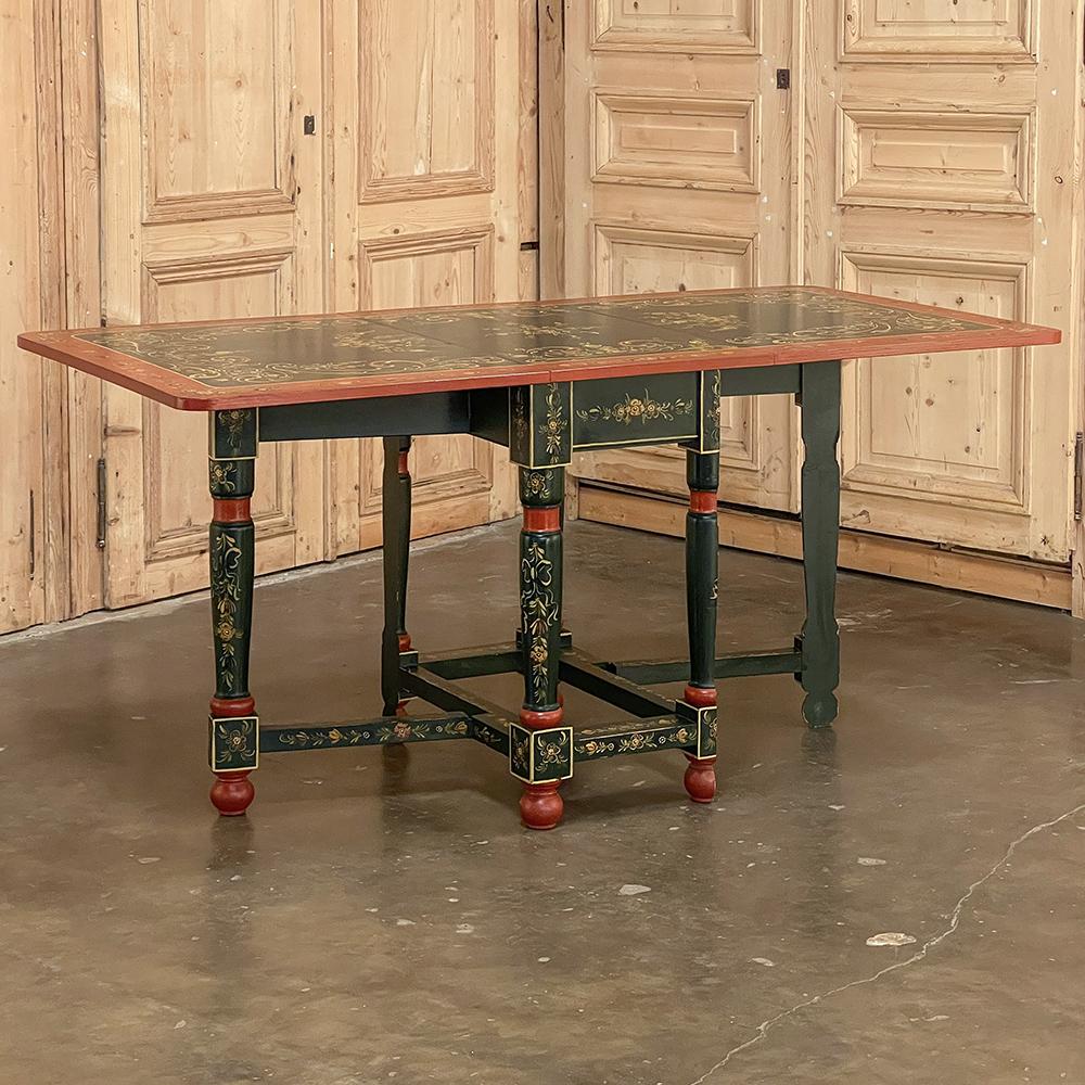19th Century Swiss hand-painted drop leaf table is a celebration of the natural spring time beauty of the Alpine country! The rich forest greens are represented as the background, with contrasting brick red bordering and trim. Fully embellished on
