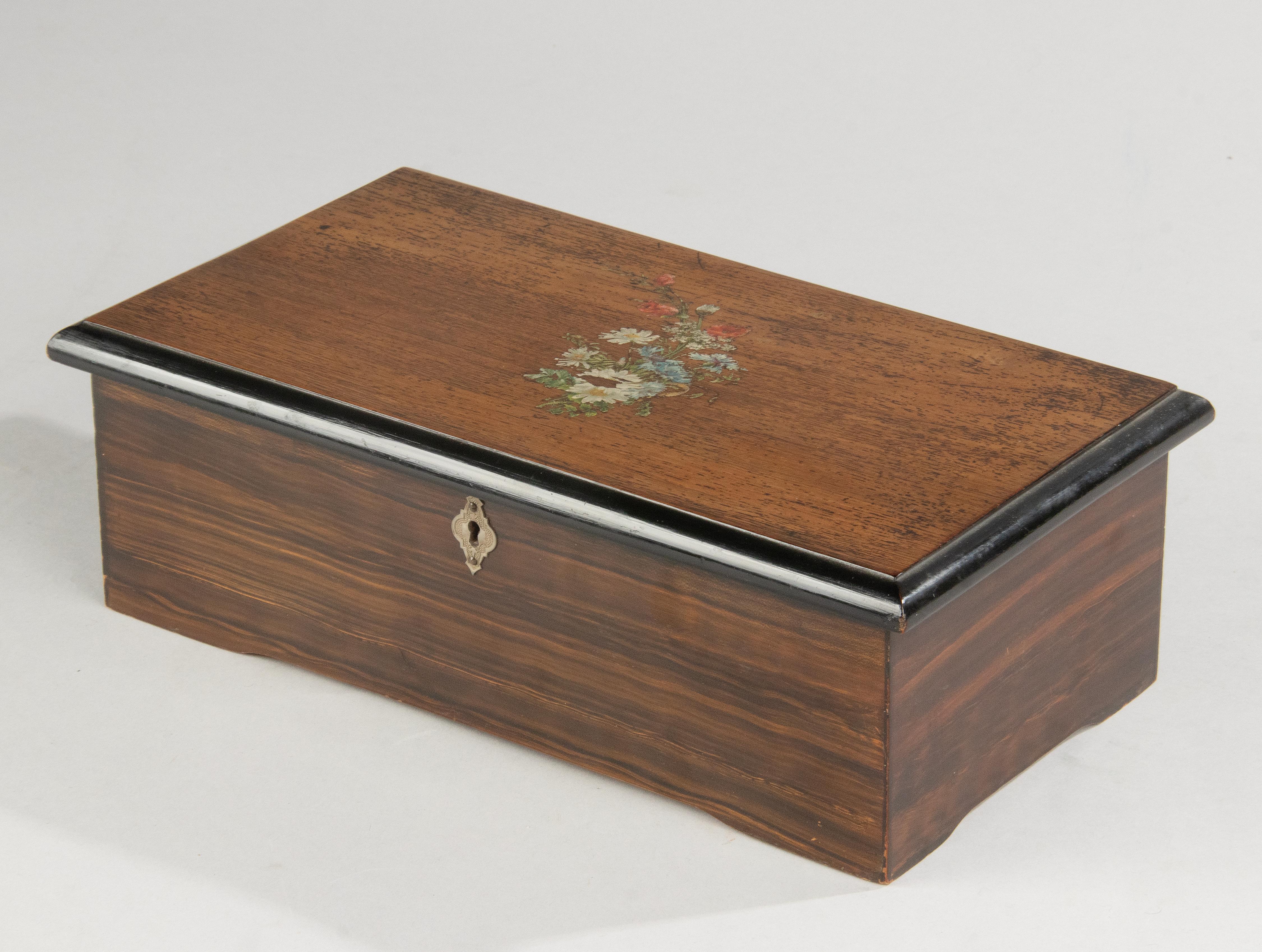 An antique 8-tunes cylinder music box. One separate tune can be played or all eight in a loop. All the tooth of the cumb are in good order. Decorative hand painted lid. The woodwork is in good condition. The songs list present on interior lid. Made