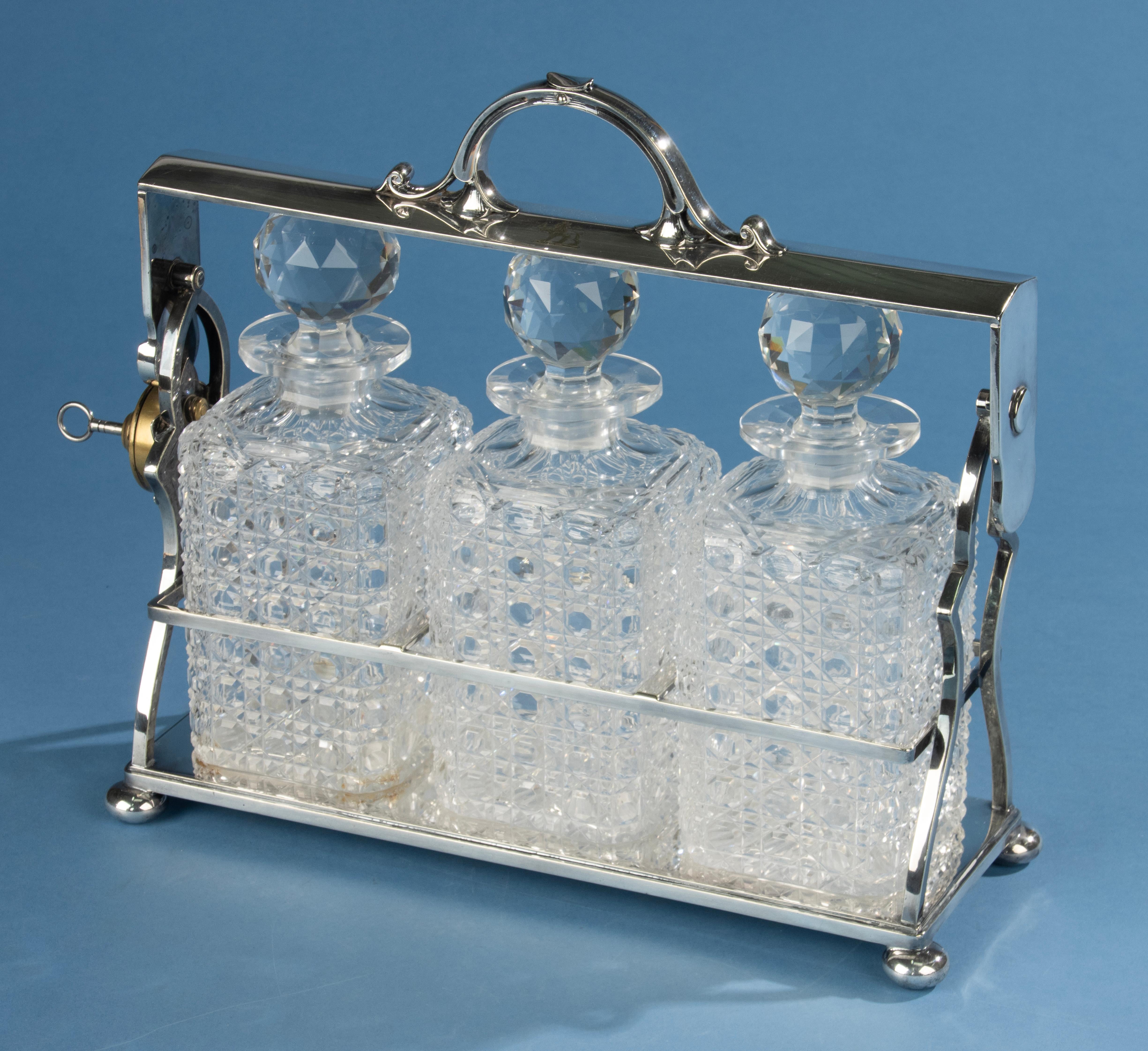 Elegant English silver-plated tantalus by Z. Barraclough & Sons, Leeds, dating from the late 19th century. This refined Victorian piece holds three beautifully cut crystal decanters with faceted stoppers. The silver-plated frame is finely crafted