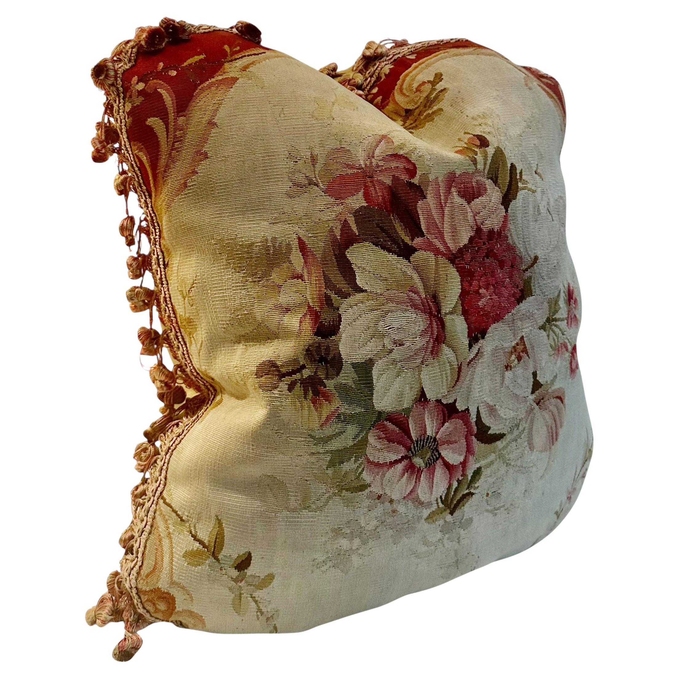 Coussin en tapisserie florale du milieu du 19e siècle. Le recto présente un magnifique motif floral tissé dans des tons sourds typiques de l'époque et est encadré d'une garniture complémentaire. Le revers est en soie riche qui ajoute une couche