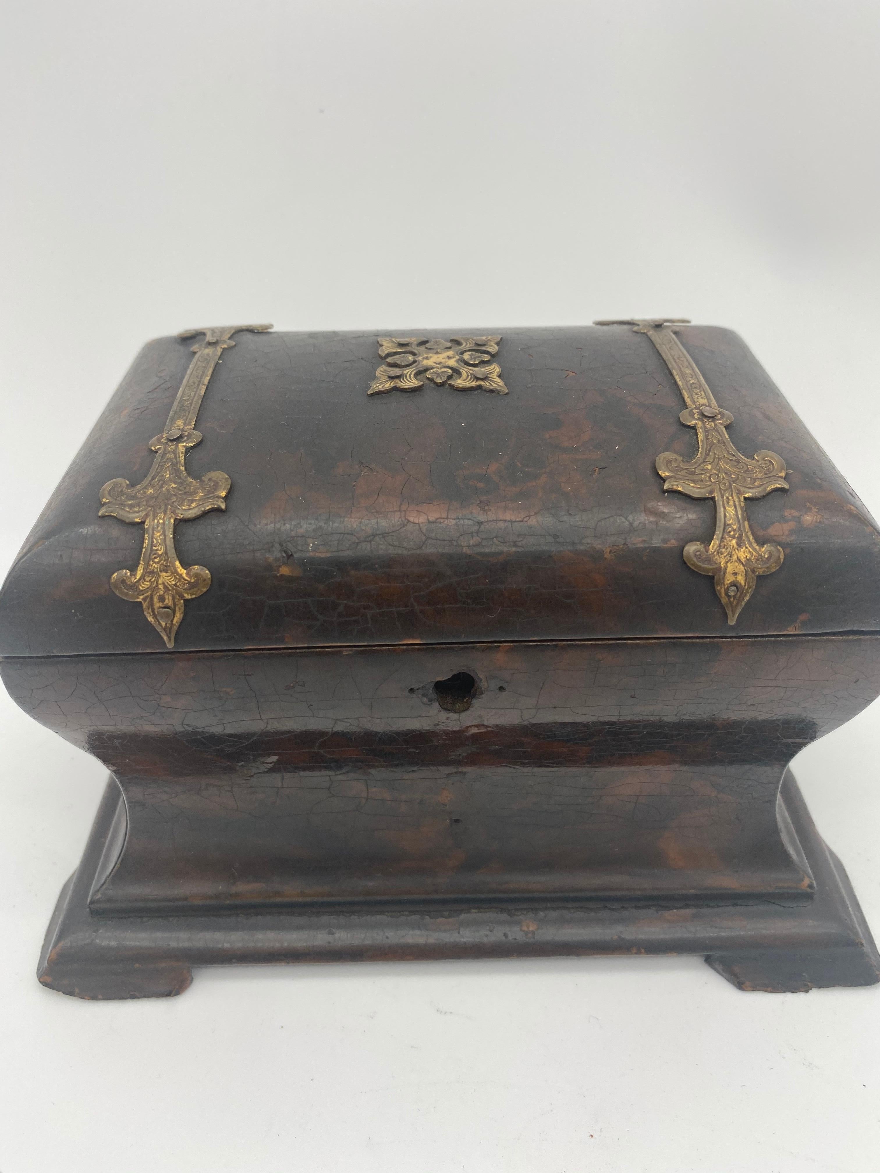 19th century lacquer tea caddy with brass ornaments. Has got an mahogany flamed color. Brass ornaments. Thick layer of lacquer over wood. Very good quality wood and is very beautiful. Some chips and age cracks. No key.