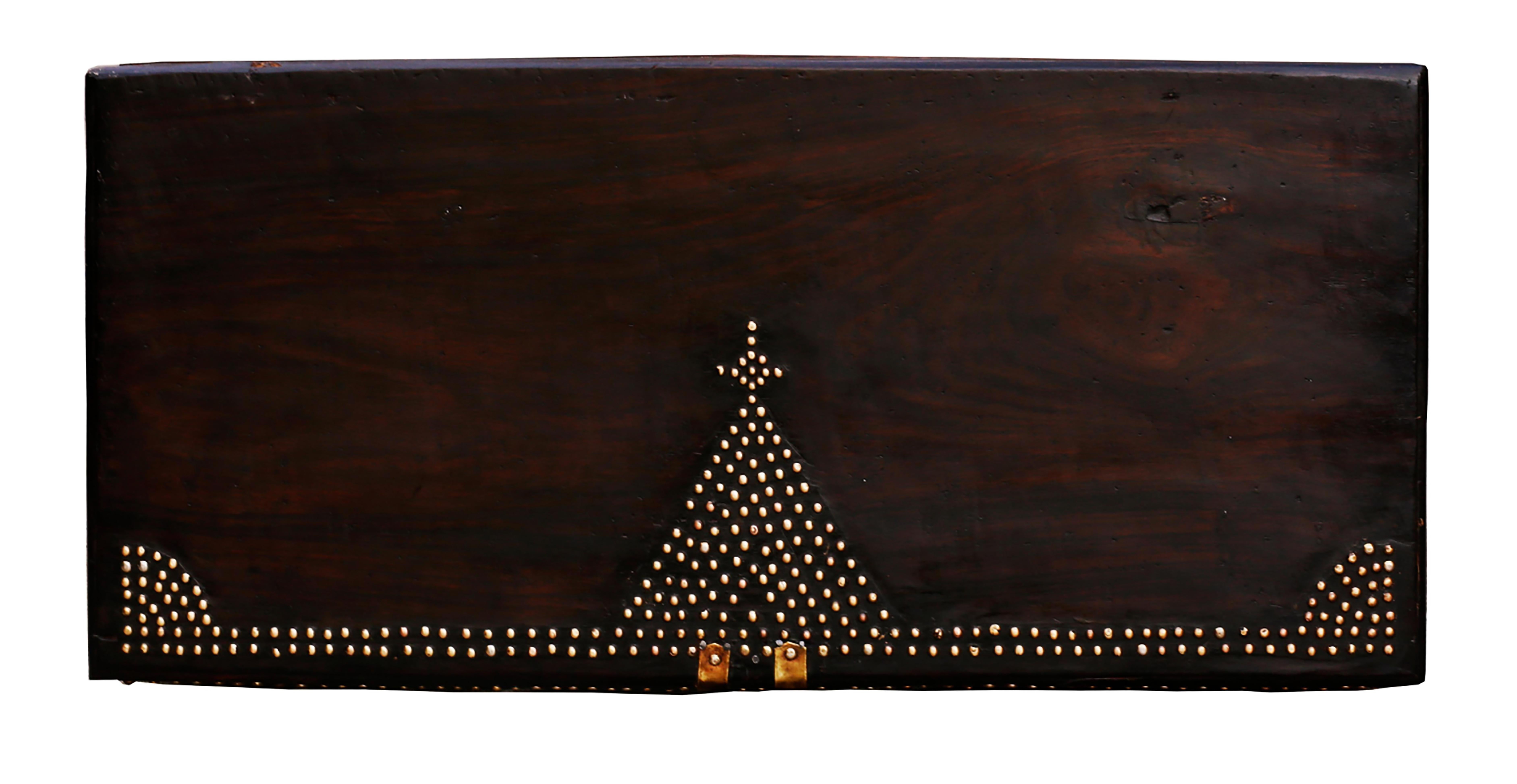 A stunning rare 19th century Zanzibar or Bombay chest composed of six thick slabs of teak wood. The exterior of the trunk is outfitted with brass sheets and studs in geometric patterns, particularly pyramidal shapes mounted by crosses, representing