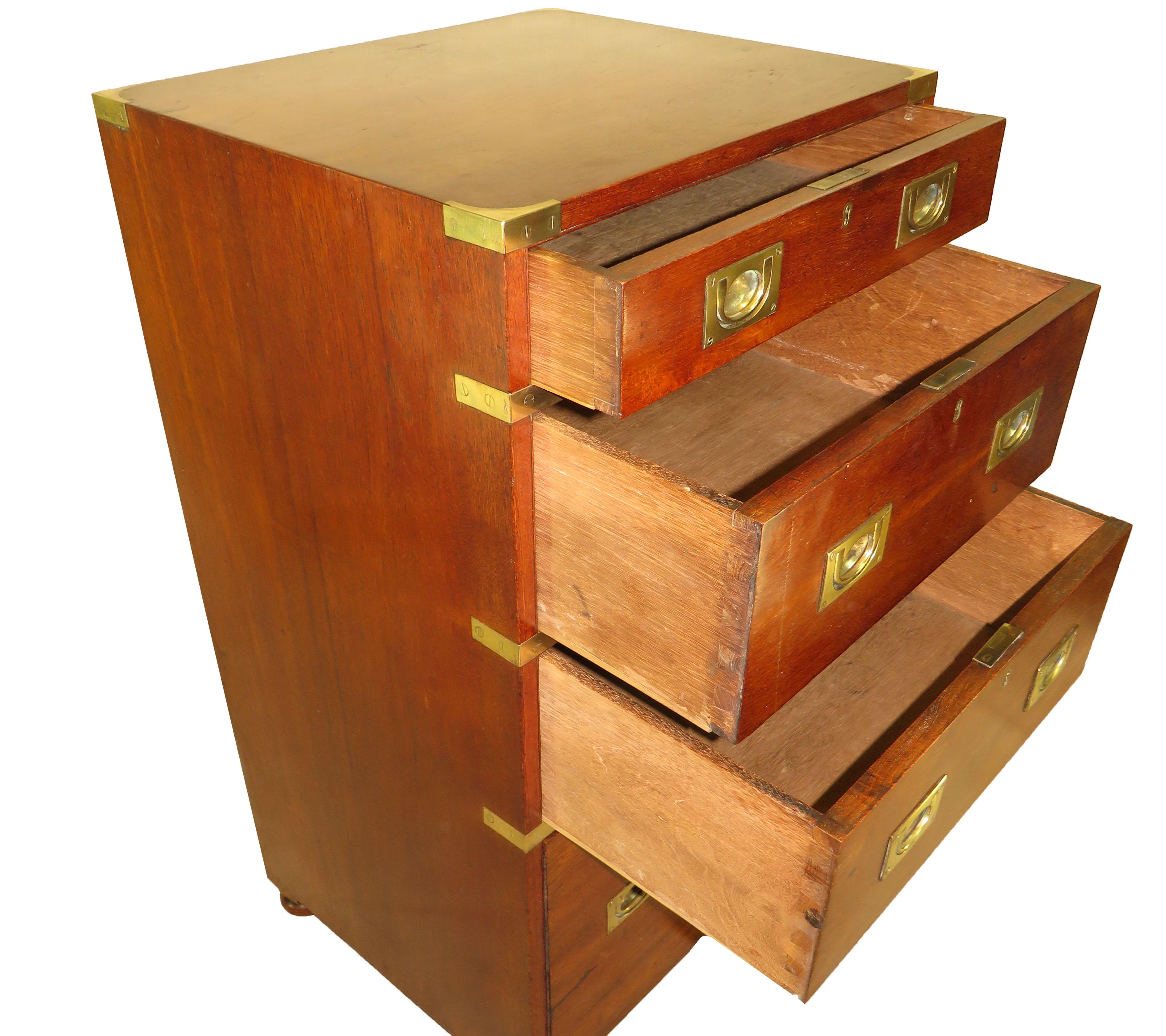 A mid-19th century teak military campaign chest of
most unusual small proportions having well figured
top over four graduated drawers retaining original
flush fitted brass handles and original brass bound
decoration raised on original turned