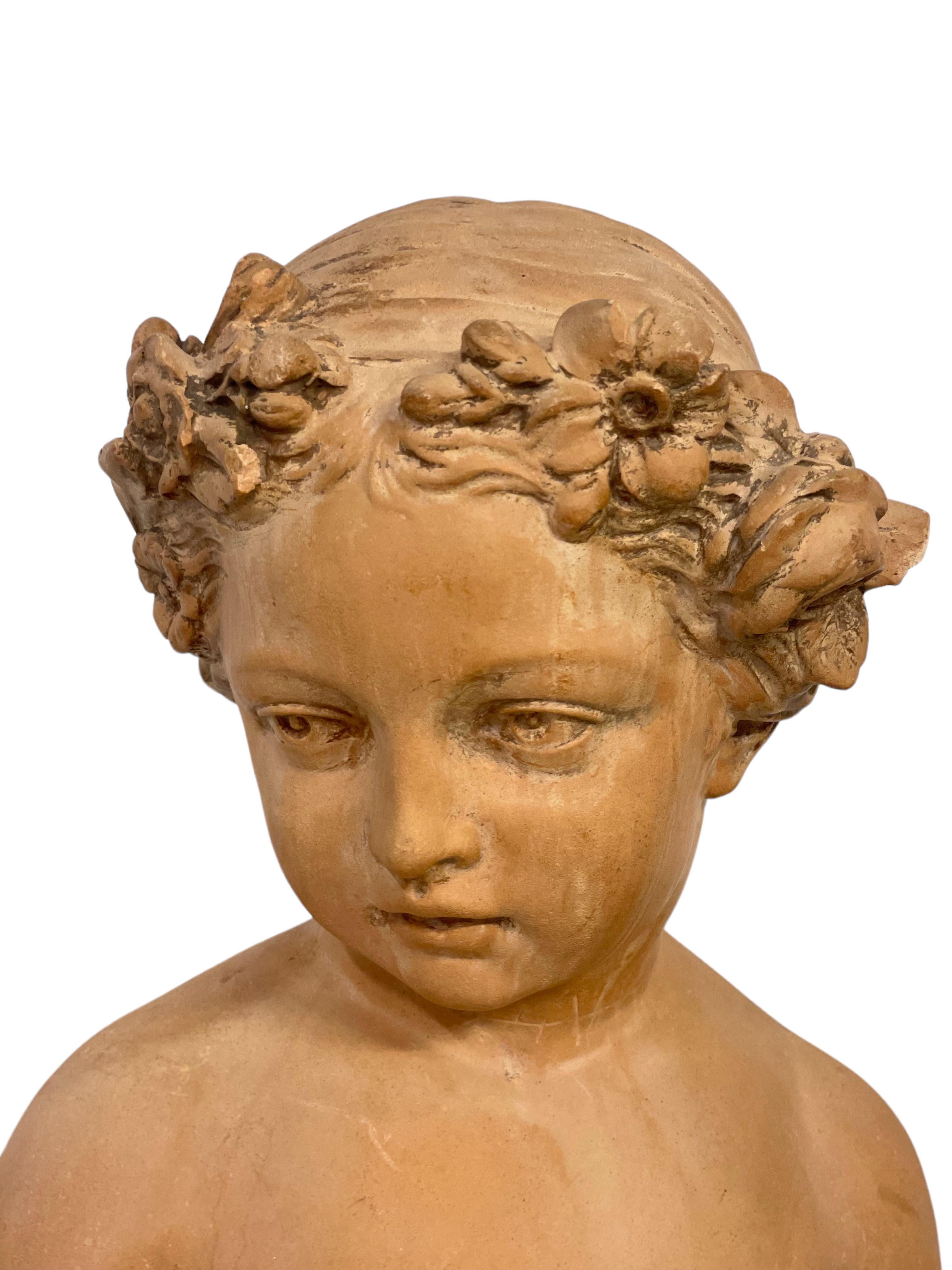 A delightful and finely detailed 18th century-style French terracotta bust of a young maiden with a wreath of flowers in her hair. This charming piece of sculpture is raised on an elegant mottled green marble plinth, and is inspired by the work of