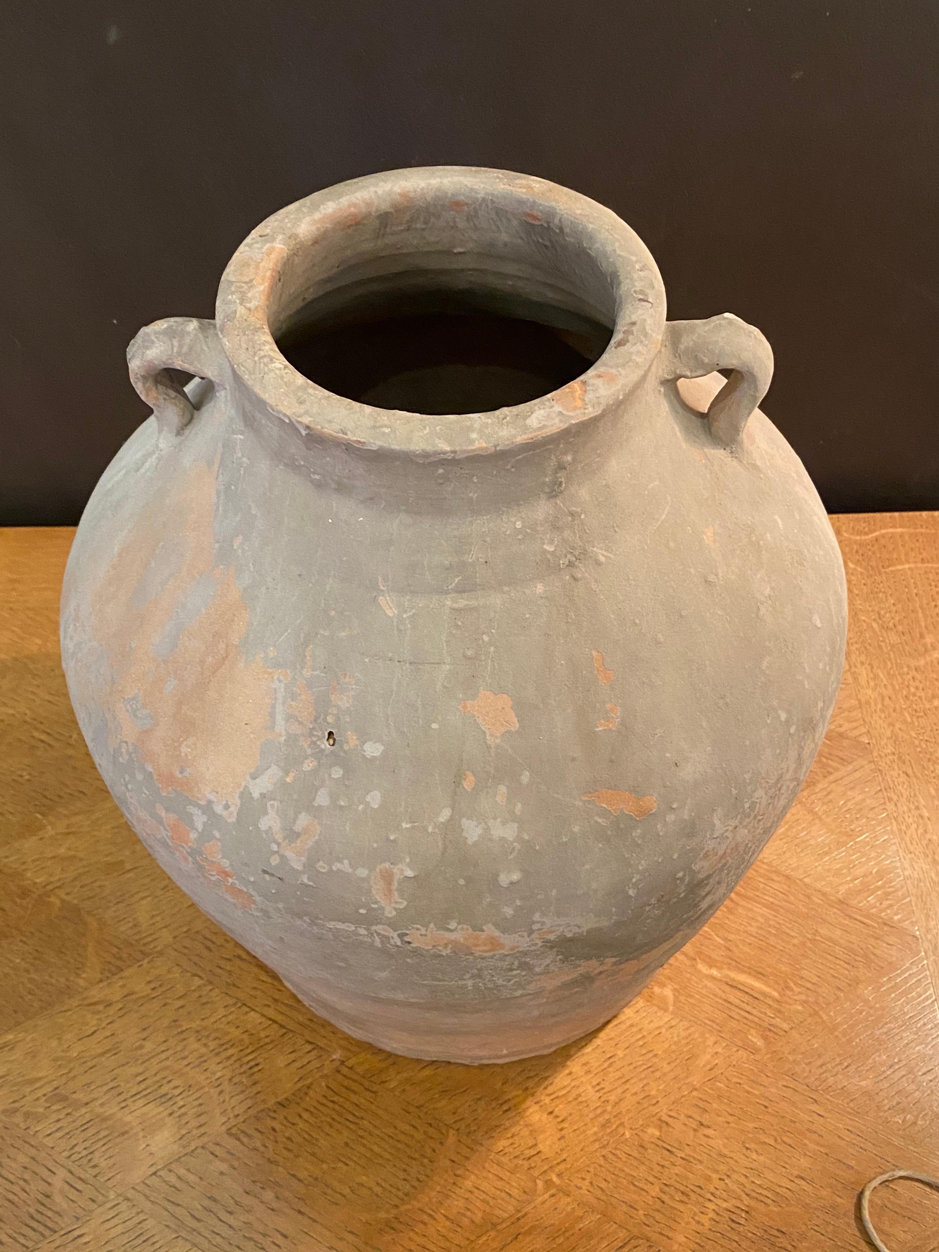 Terracotta pot from 19th century China that was used to store water or grain.
The weathered terracotta vessel has two small handles at the neck.

 