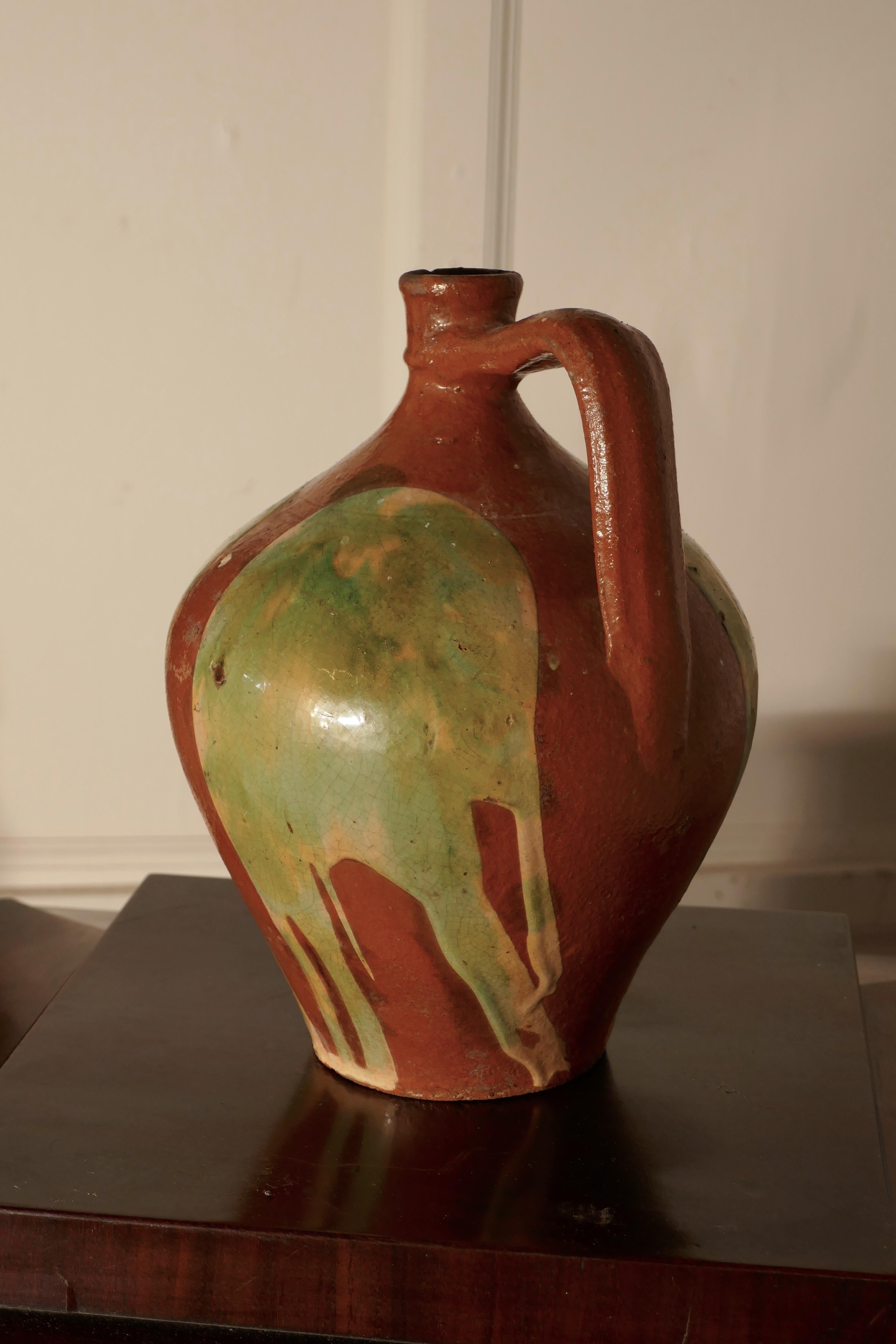 19th century terracotta olive oil jug from Portugal. 

A wonderful Portuguese antique olive oil jar, this piece has a beautiful shape, handle to one side and a very attractive bright pattern under the glaze, not perfect but in very good condition
