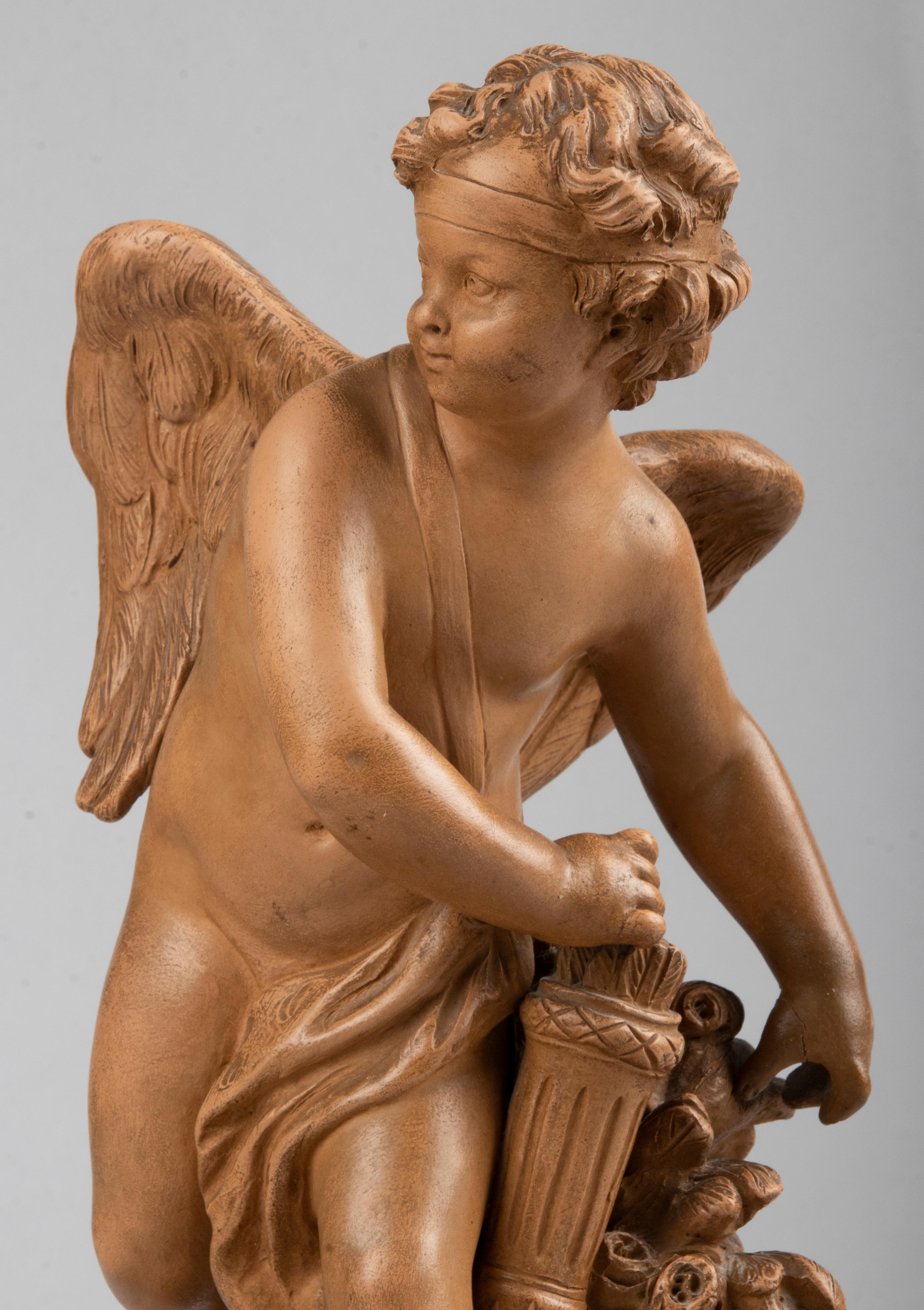 Belle sculpture ancienne en terre cuite, représentant Cupidon prenant une flèche de son carquois pour la tirer avec son arc. La statue s'inspire d'une célèbre œuvre du 18e siècle réalisée par le sculpteur Etienne Maurice Falconet (1716-1791). La