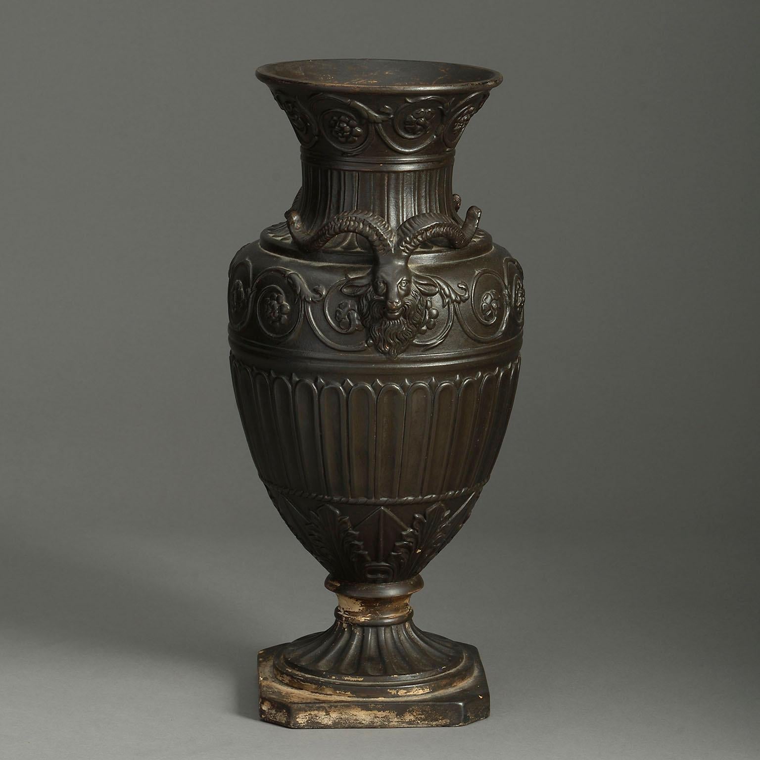 A mid-nineteenth century terracotta urn in the Classical taste, the neck with scrolling floral work above a palmette frieze, with applied rams head handles, the body having repeated floral scrollwork upon fluting and palmette and acanthus