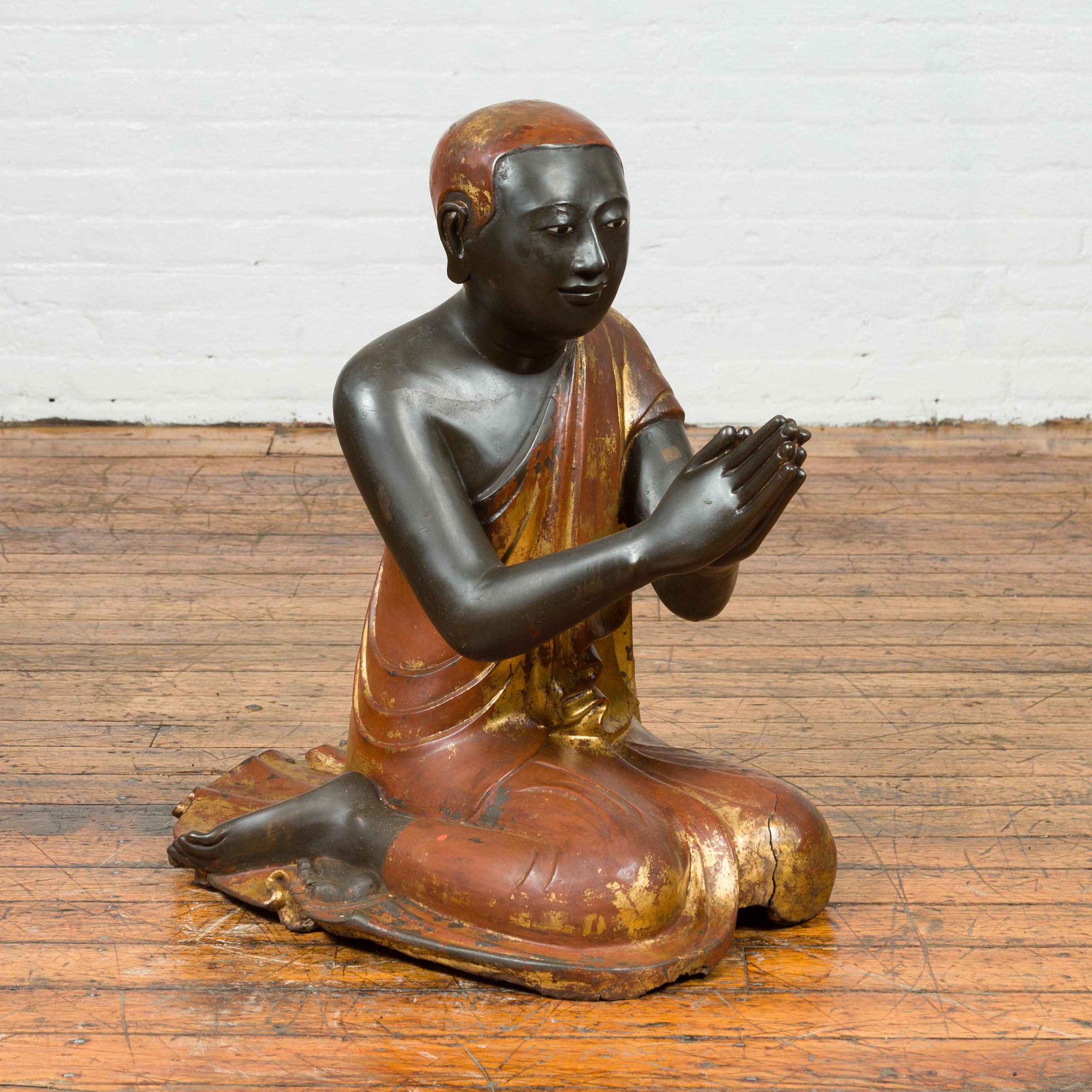 A Thai kneeling ceremonial monk sculpture from circa 1920 with hand painted gilt and lacquer over stone. This remarkable Thai ceremonial kneeling monk sculpture, discovered within a temple, is an extraordinary artifact of spiritual significance.