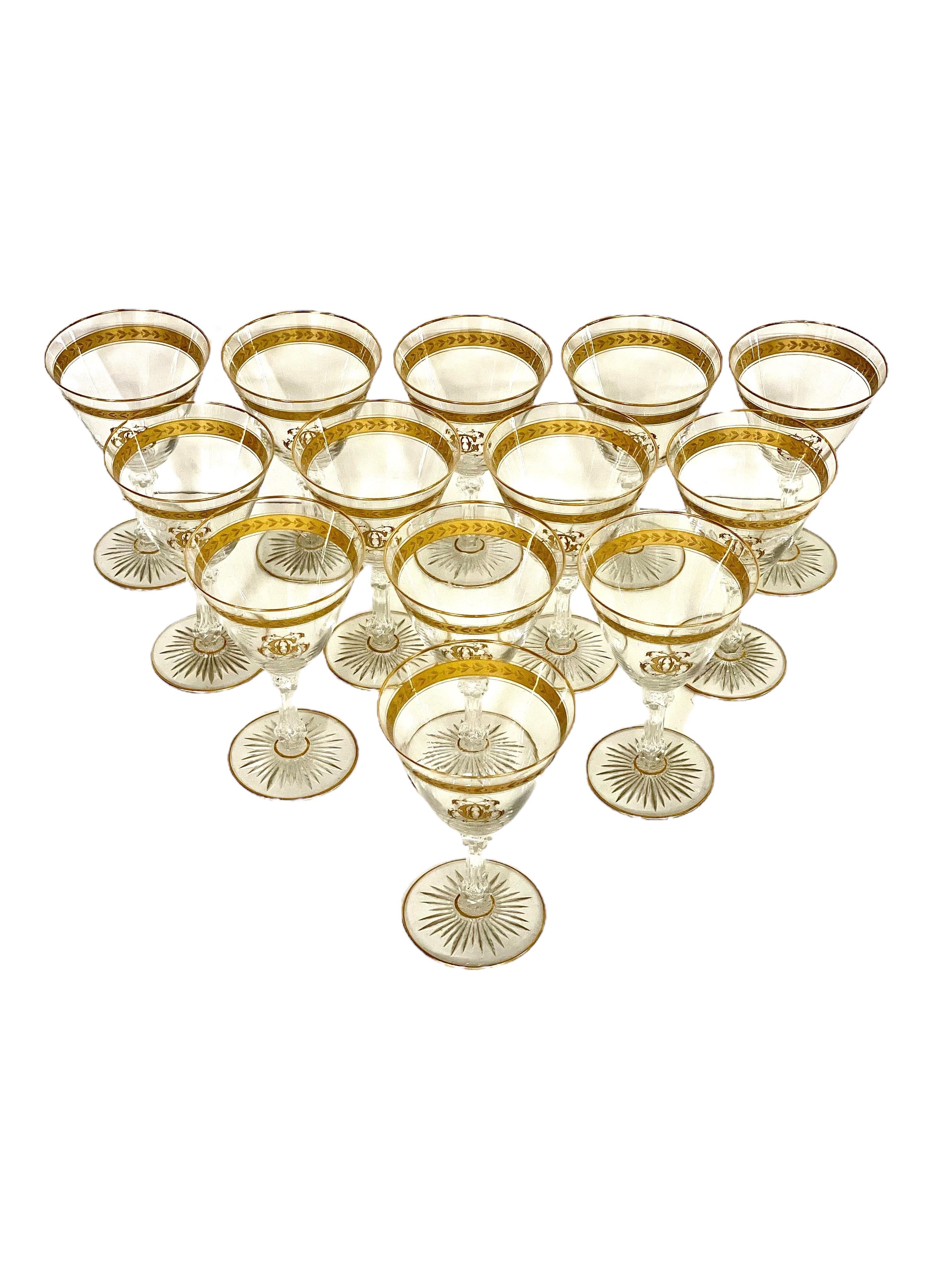 Elegante juego de trece copas de vino de cristal del siglo XIX, cada una generosamente adornada con un borde dorado y una banda superior de hojas de laurel doradas, y con un elaborado monograma 