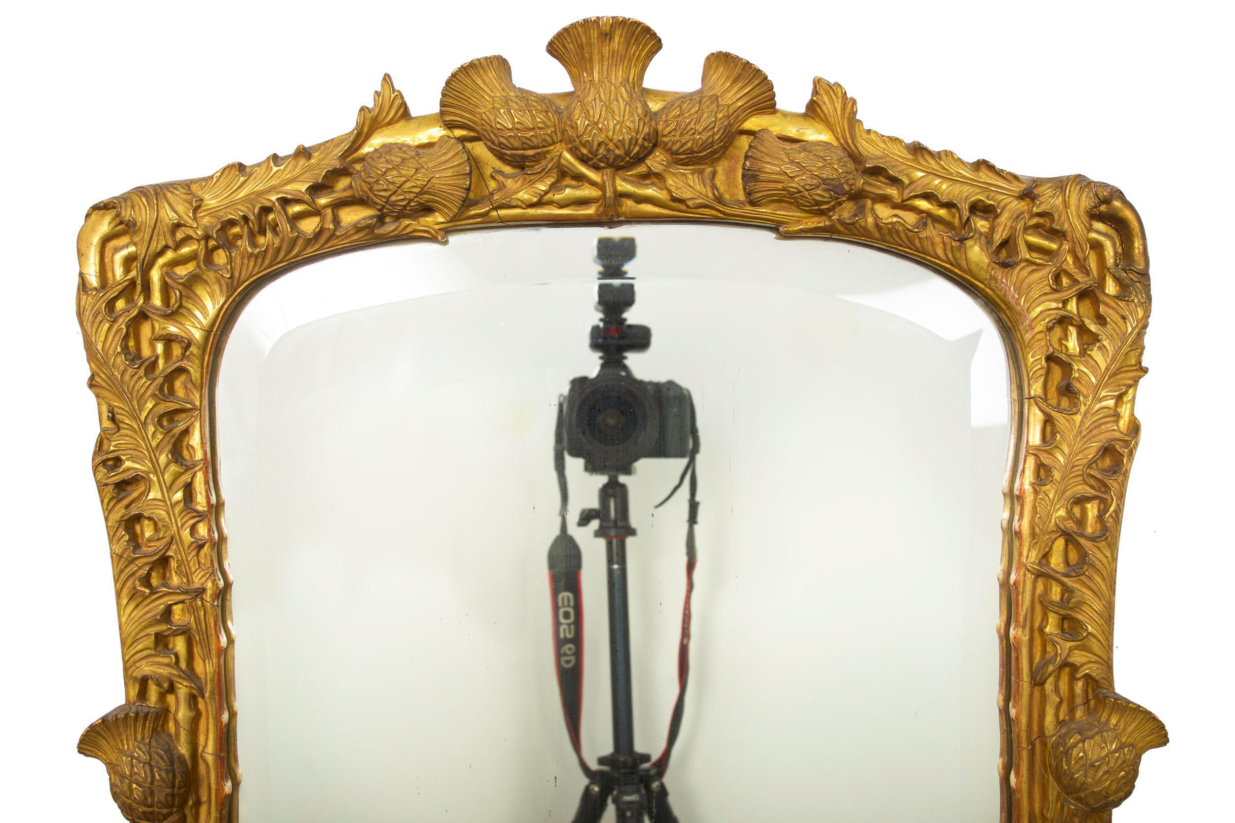 This incredibly fine and truly exquisite giltwood mirror features a dramatic overall carved frame with representations of thistles, roses and the thorny stalks lining the frame surrounding a beveled mirror. Crafted during the third quarter of the