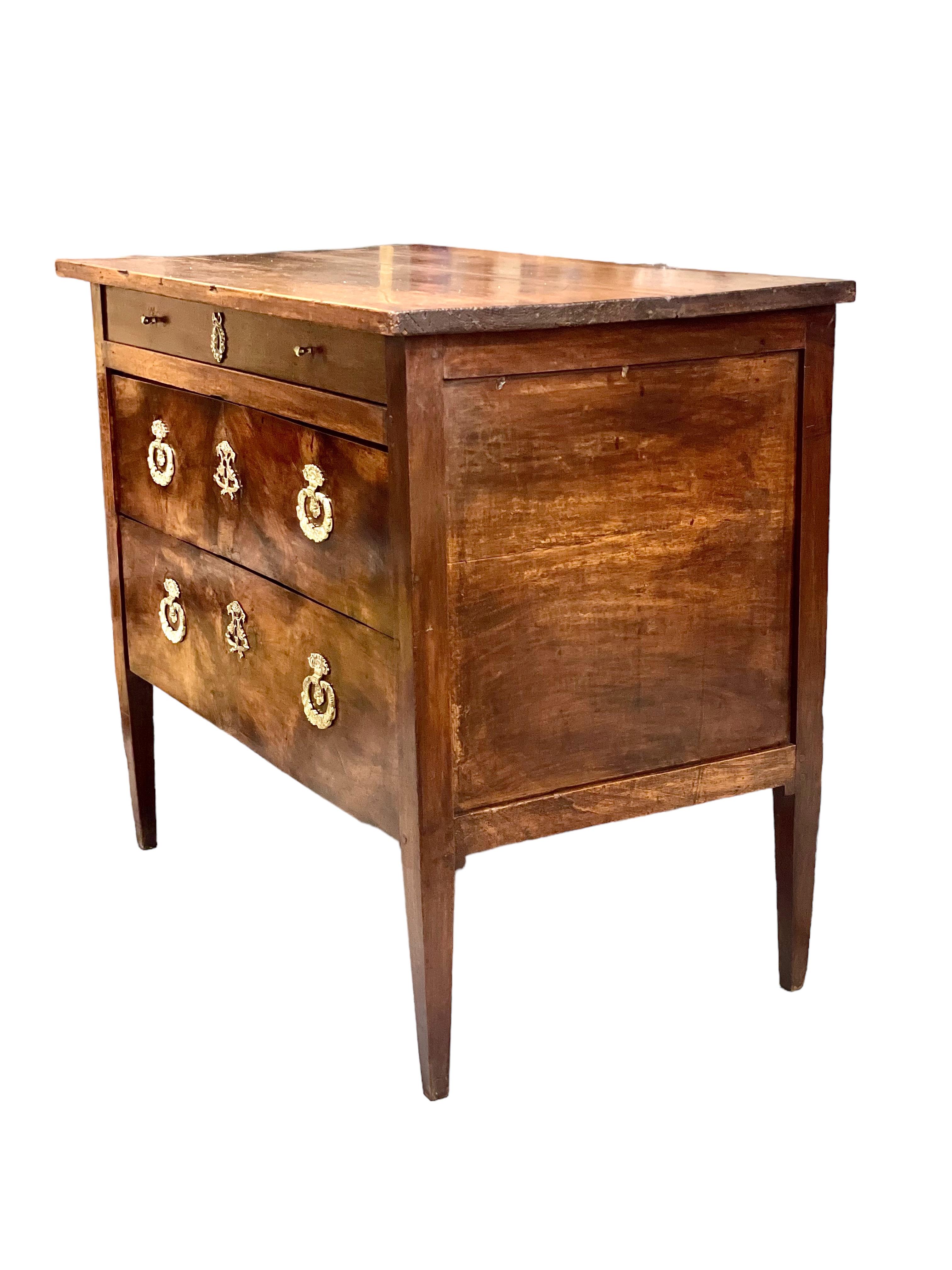 A simple and elegant 19th century commode, finished in beautiful wood veneer. Opening with two deep and wide drawers below a shallower one, its proportions make it an ideal piece for storage of important paperwork or maps. This handsome chest rests