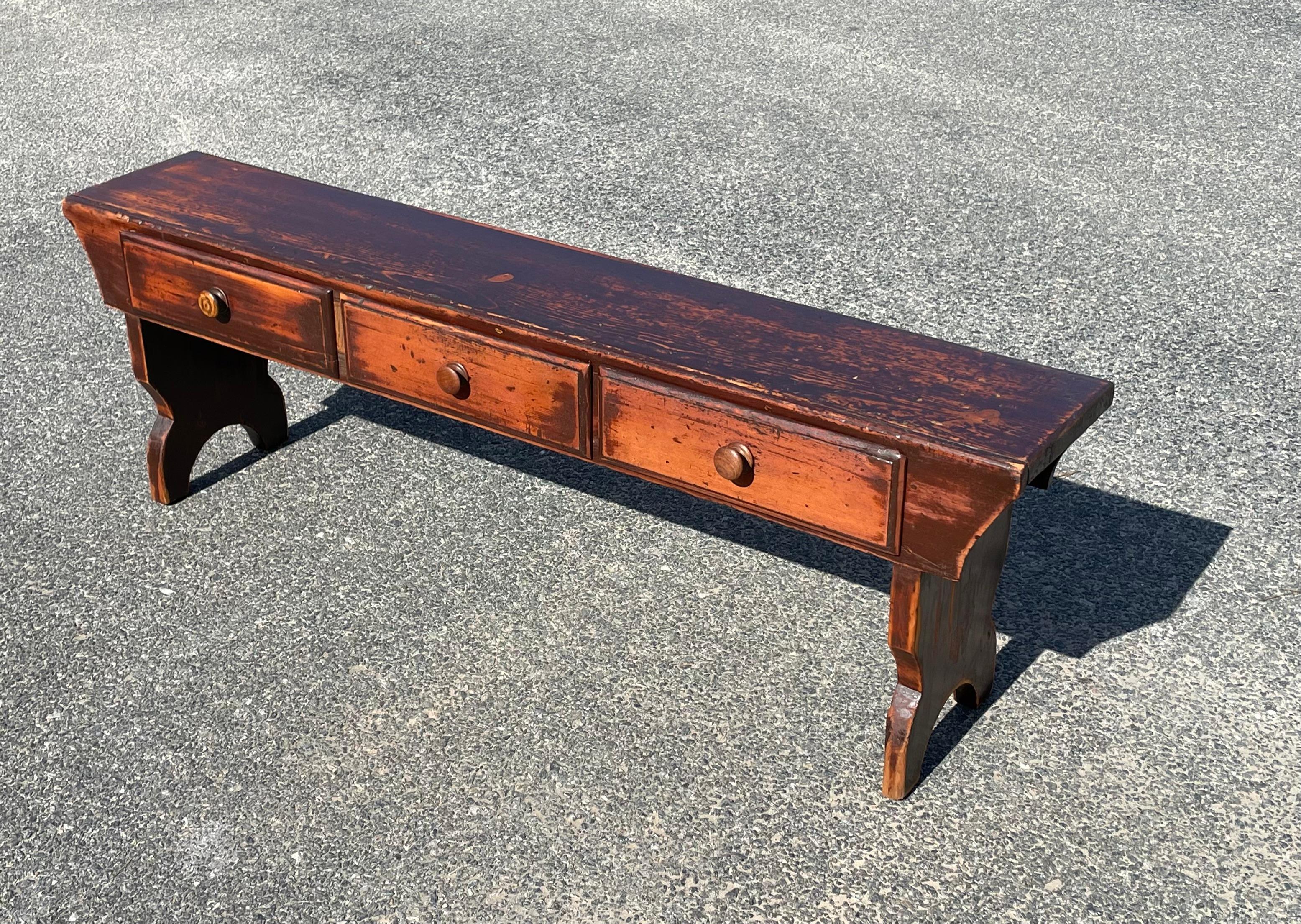 19th century pine bench in early brown paint.  With three drawers and bootjack legs.  