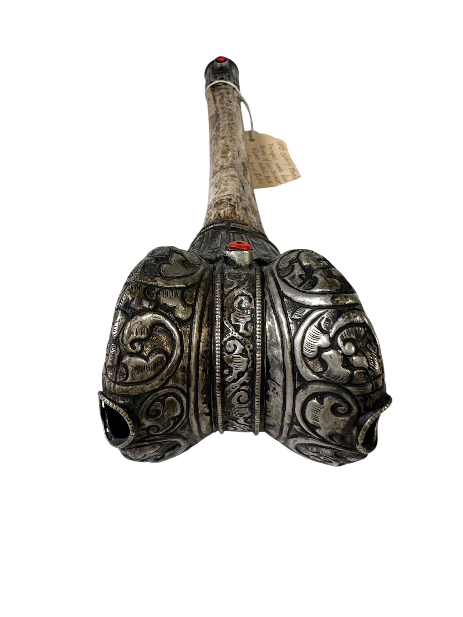 Una straordinaria tromba rituale tibetana, tradizionalmente nota come kangling, realizzata con un osso di femore umano e ornata con metalli a basso contenuto di argento e perline di corallo montate. Questi strumenti cerimoniali venivano utilizzati