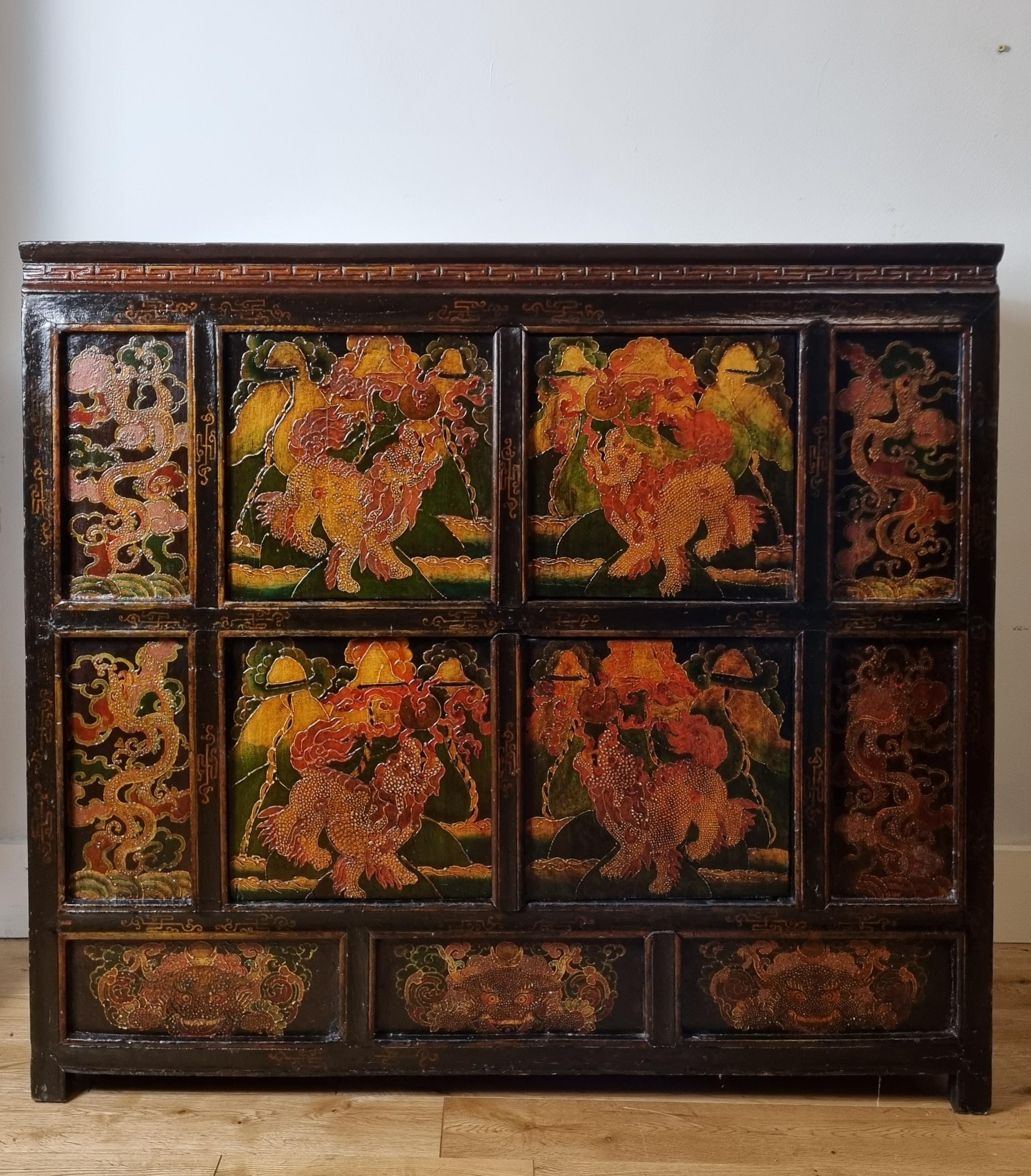A Tibetan polychrome hand-painted cabinet dating from the mid to late 19th century. It features eight beautifully painted panels with an extremely rare foo dogs and dragon design surrounded by leafy foliage. The cabinet has four pivoting central
