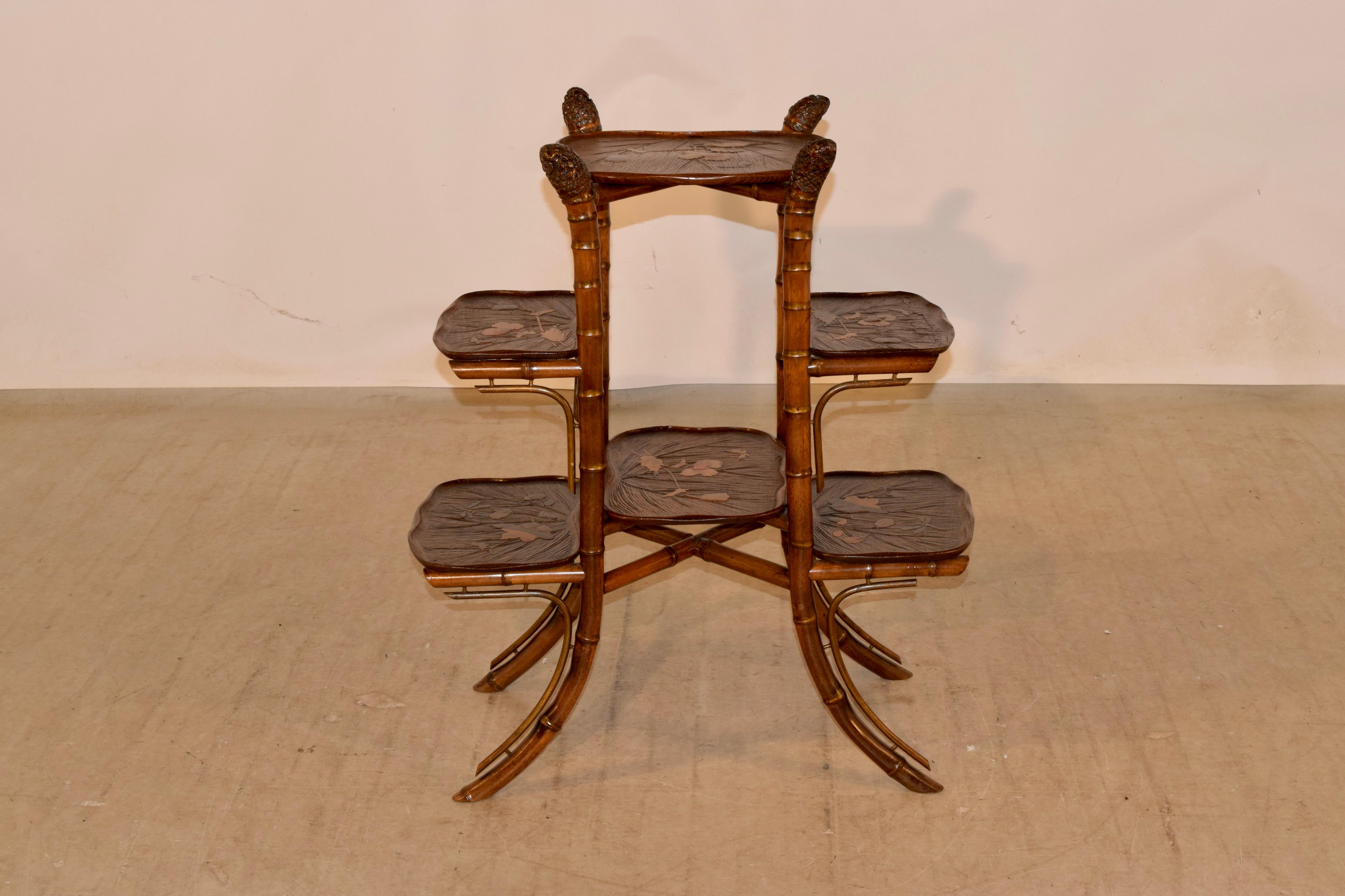 19th century bamboo tiered table from France with hand carved fruitwood shelves. The top of the legs are the roots of the bamboo, which has been artfully used as a decorating feature on this table. The legs are gracefully splayed, and have hand