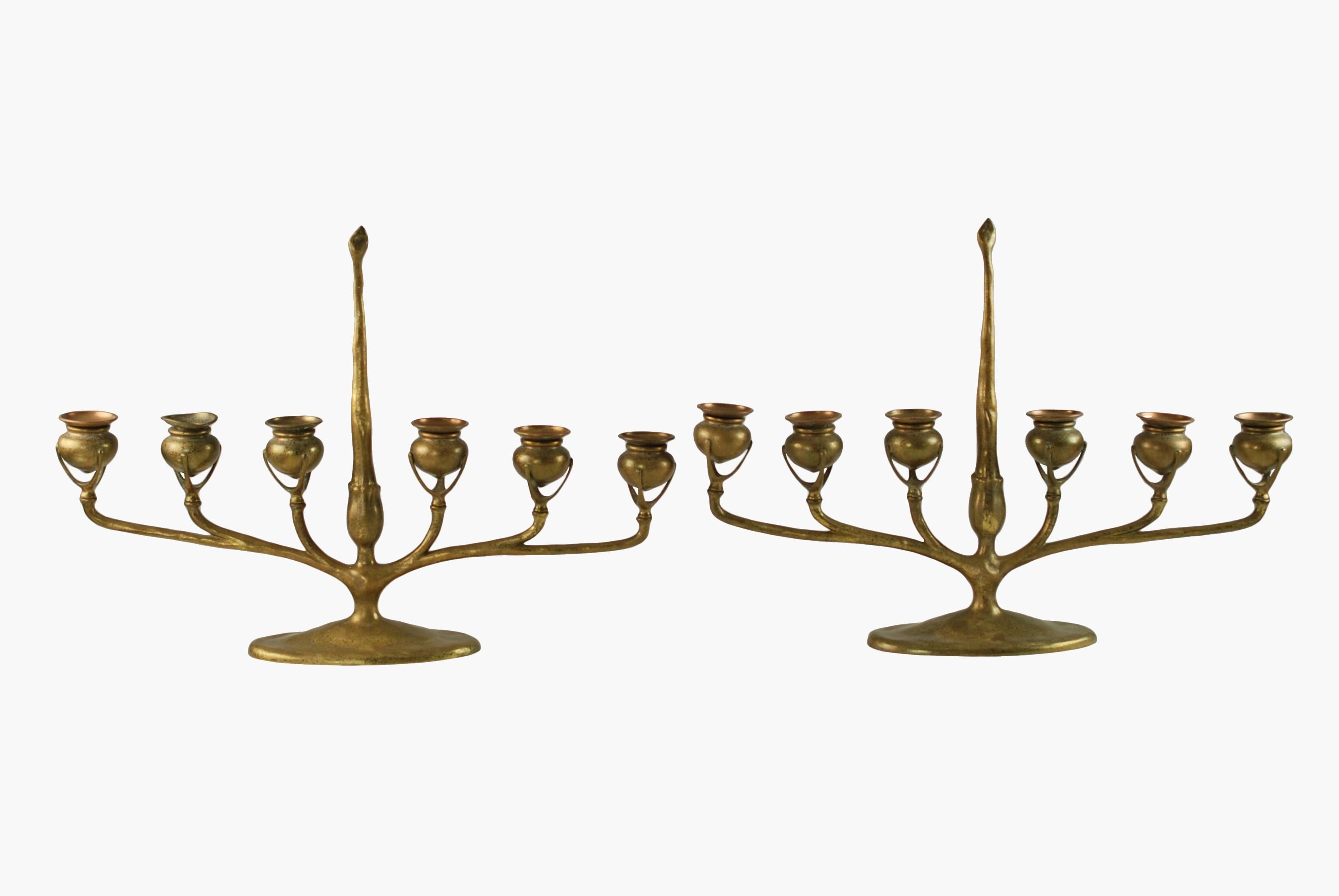 This matched pair of Art Nouveau gilt bronze candelabra were made by Tiffany Studios of New York. The candelabra have an naturalistic form modeled after tree branches and feature six arms, each of which are finished with a trio of slender supports