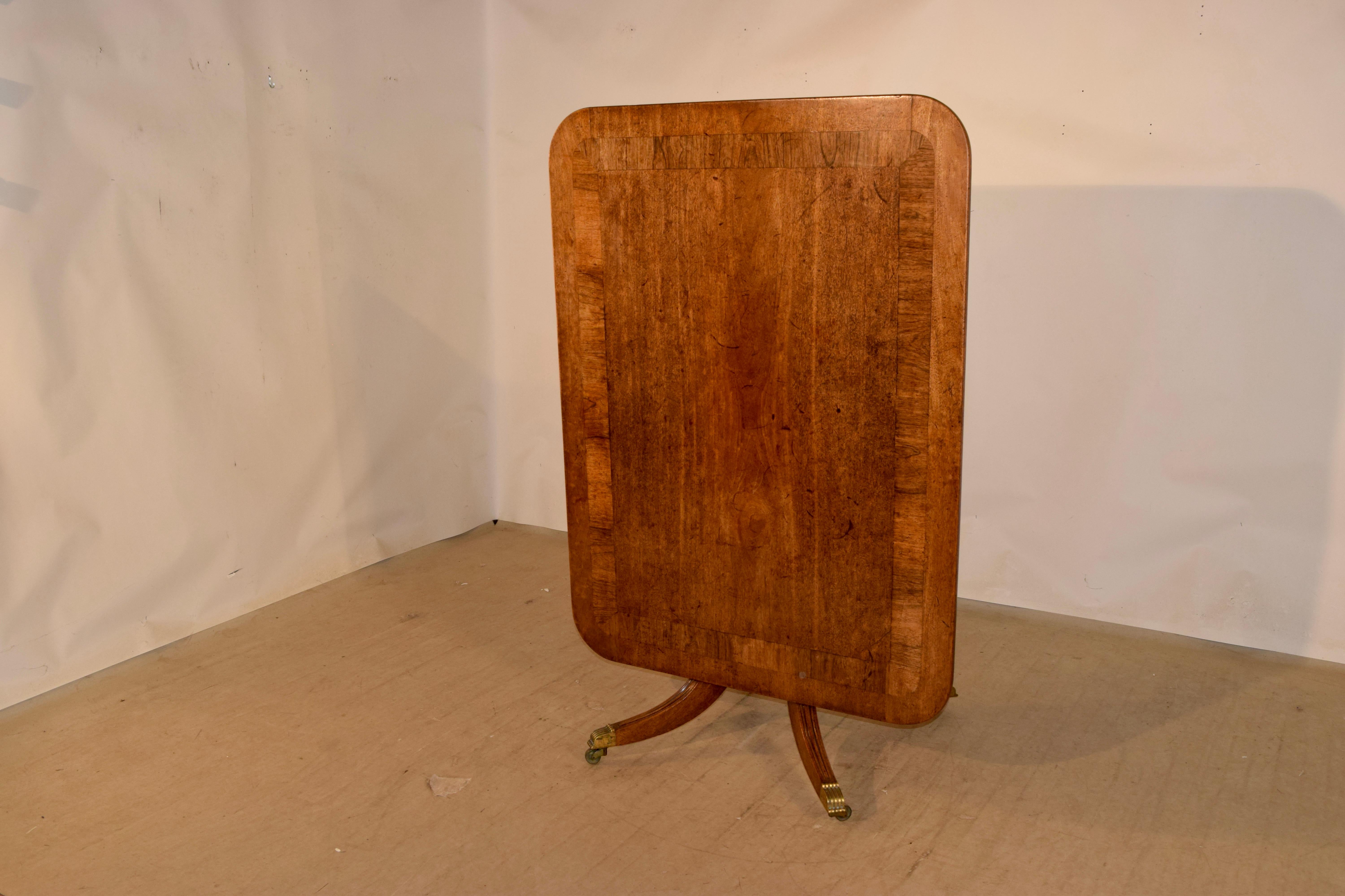 table de petit déjeuner à plateau basculant du 19e siècle en Angleterre. La table est en acajou et présente un magnifique bandeau en bois de rose autour du plateau, au-dessus d'une colonne centrale tournée et soutenue par quatre pieds, qui