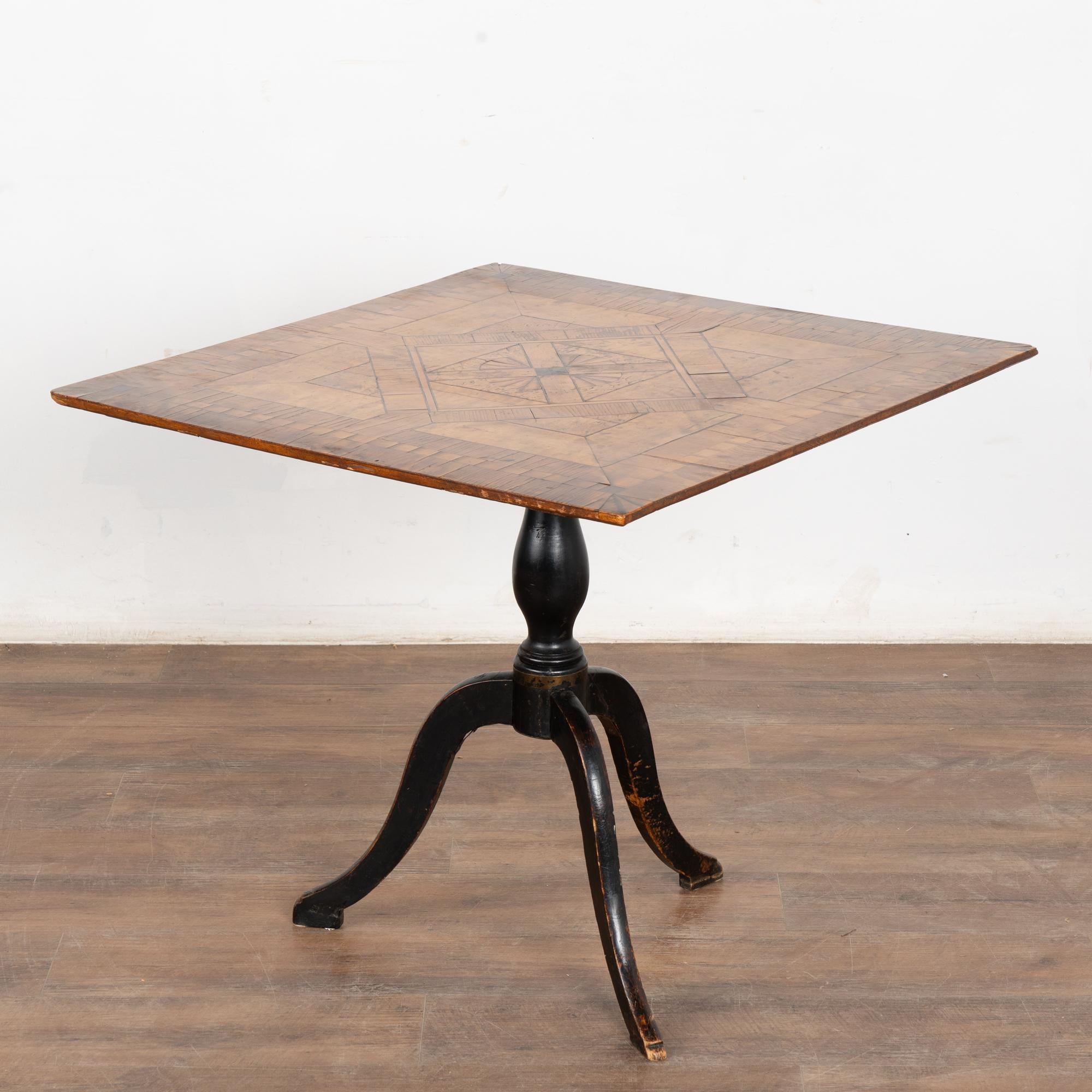 La base originale peinte en noir accentue la chaleur du magnifique plateau marqueté de cette table d'appoint à plateau basculant, qui était probablement utilisée à l'origine comme table à thé.
La patine vieillie du plateau est le reflet de plusieurs