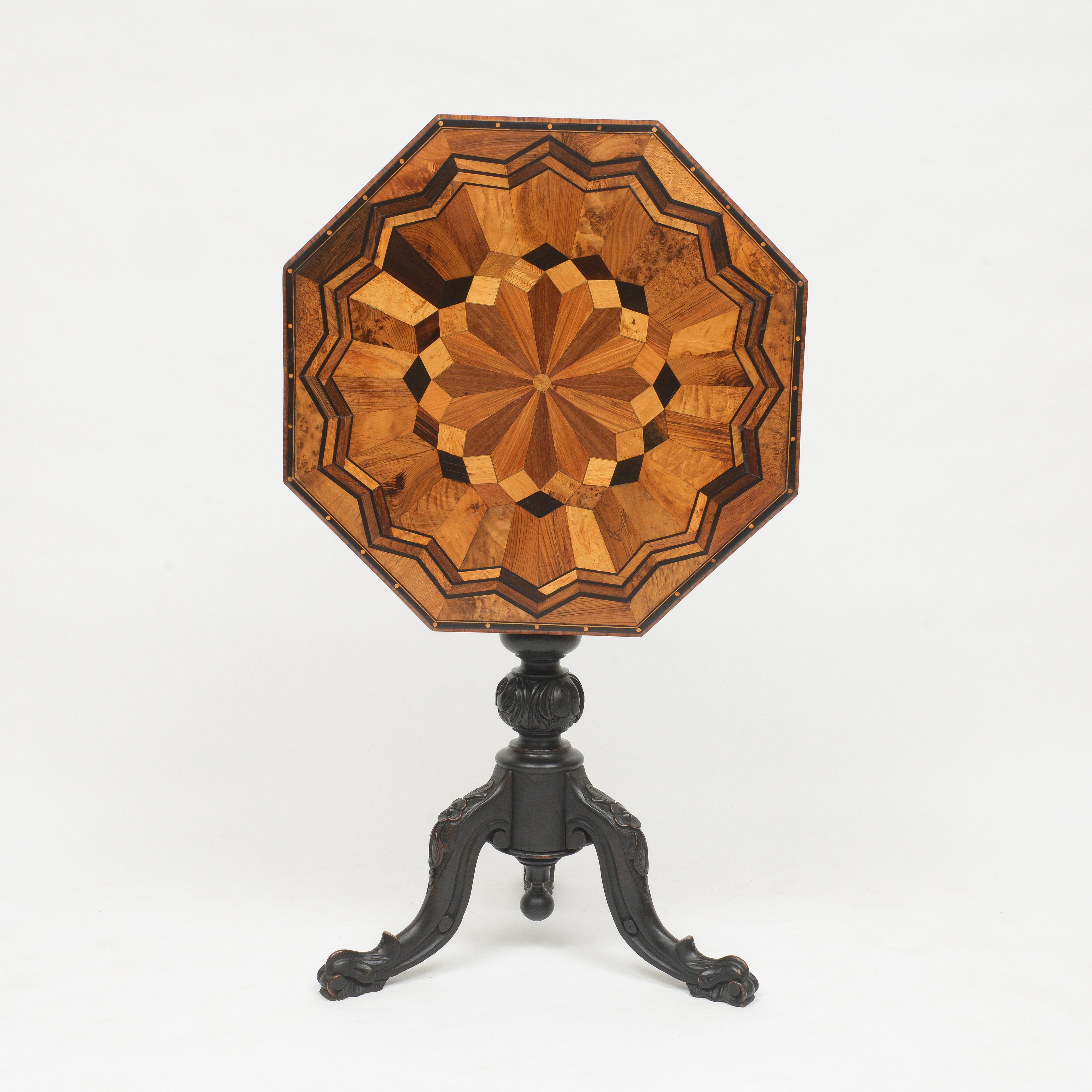 The octagonal table top is arranged in a parquetry design that is composed of many different veneer arranged in an elaborate patera pattern. The base is a series of turnings ending in three carved legs. Excellent condition