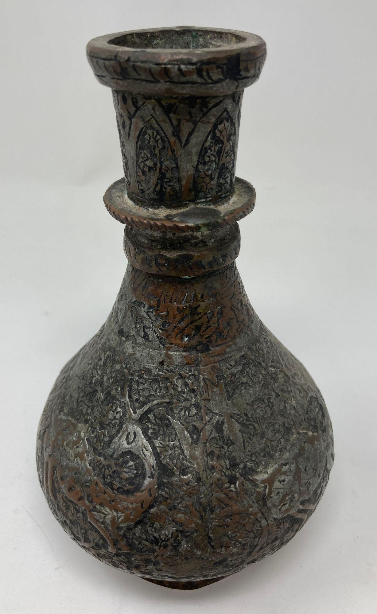 Antike islamische Kupferflasche aus Metall mit kugelförmigem Boden, verziert mit einem vertieften, sich wiederholenden floralen und geometrischen Motiv mit einer Hirschfigur.
19. Jahrhundert Indo-persische islamische Vase aus verzinntem Kupfer,