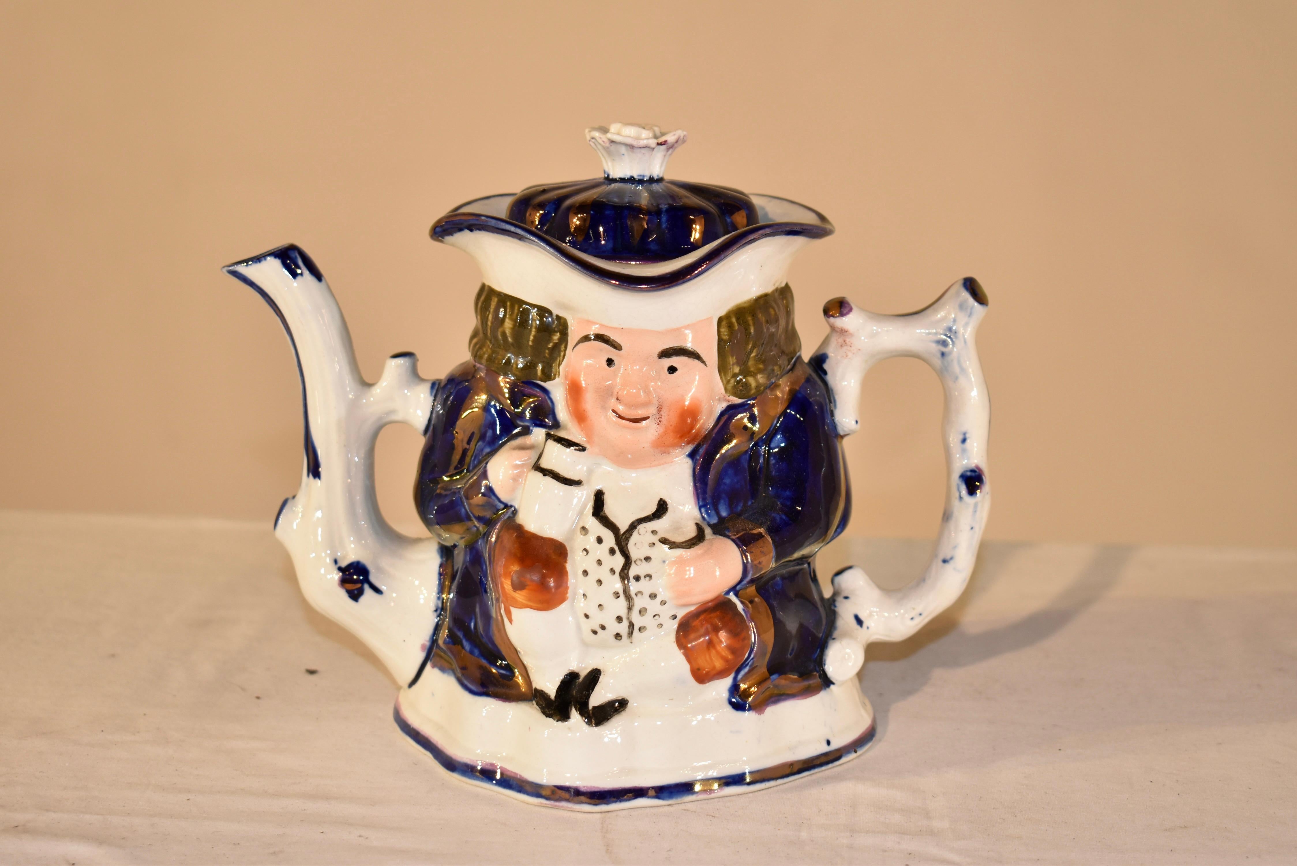 19th century Toby tea pot from the Staffordshire region of England.  The top is in a scalloped shape and is a brilliant cobalt color with copper lustre embellishment.  It is topped with a ceramic top for which to lift the lid.  The tea pot itself is