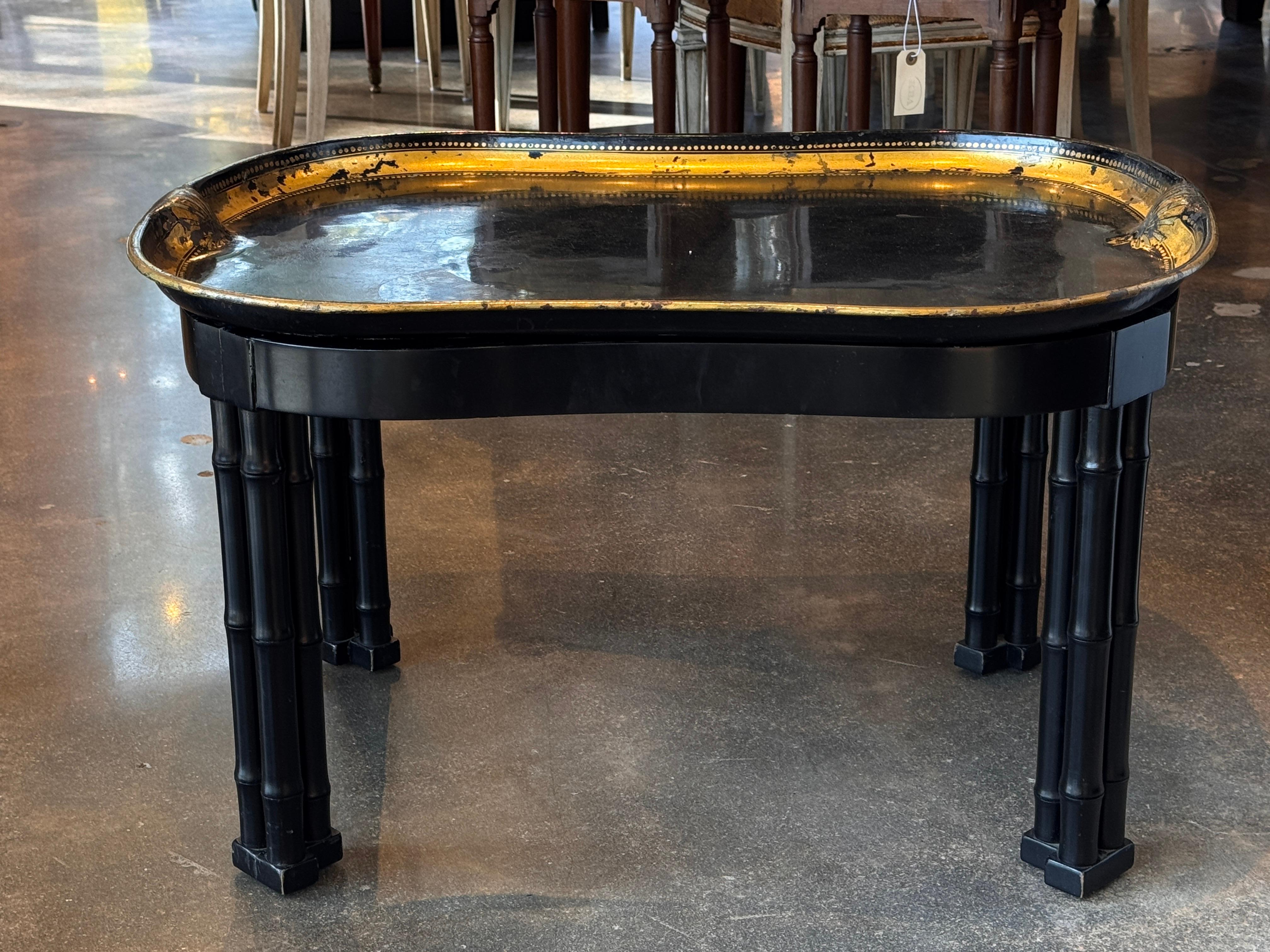 Plateau en tole noir du 19e siècle avec bordure dorée et bord festonné, reposant sur un support en faux-bambou personnalisé plus tardif. Le plateau présente une patine vieillie et des détails dorés peints à la main, comme le montre le gros plan. Un