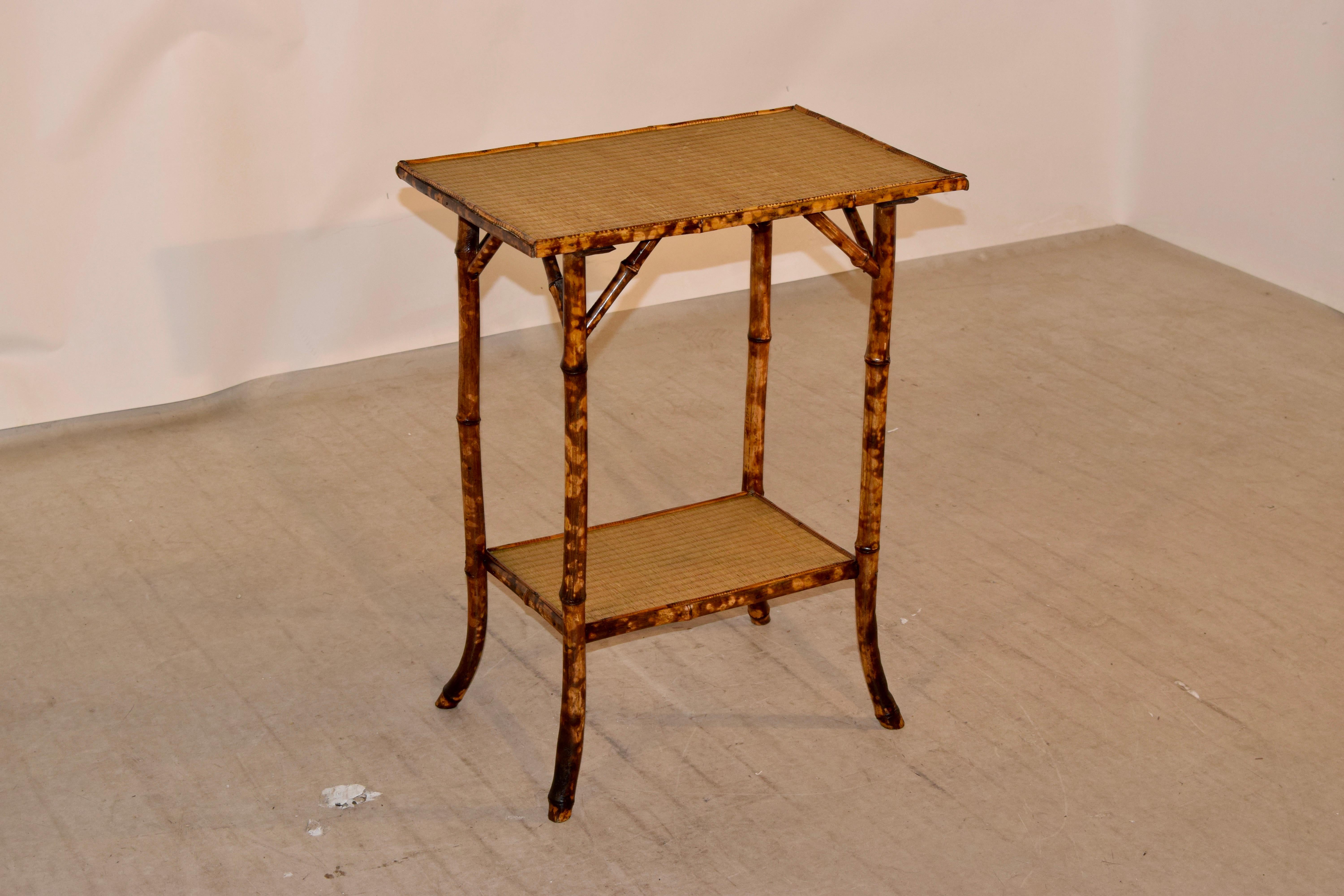 19th century tortoise bamboo side table from France with a rush covered top and lower shelf. The table is supported on splayed legs.