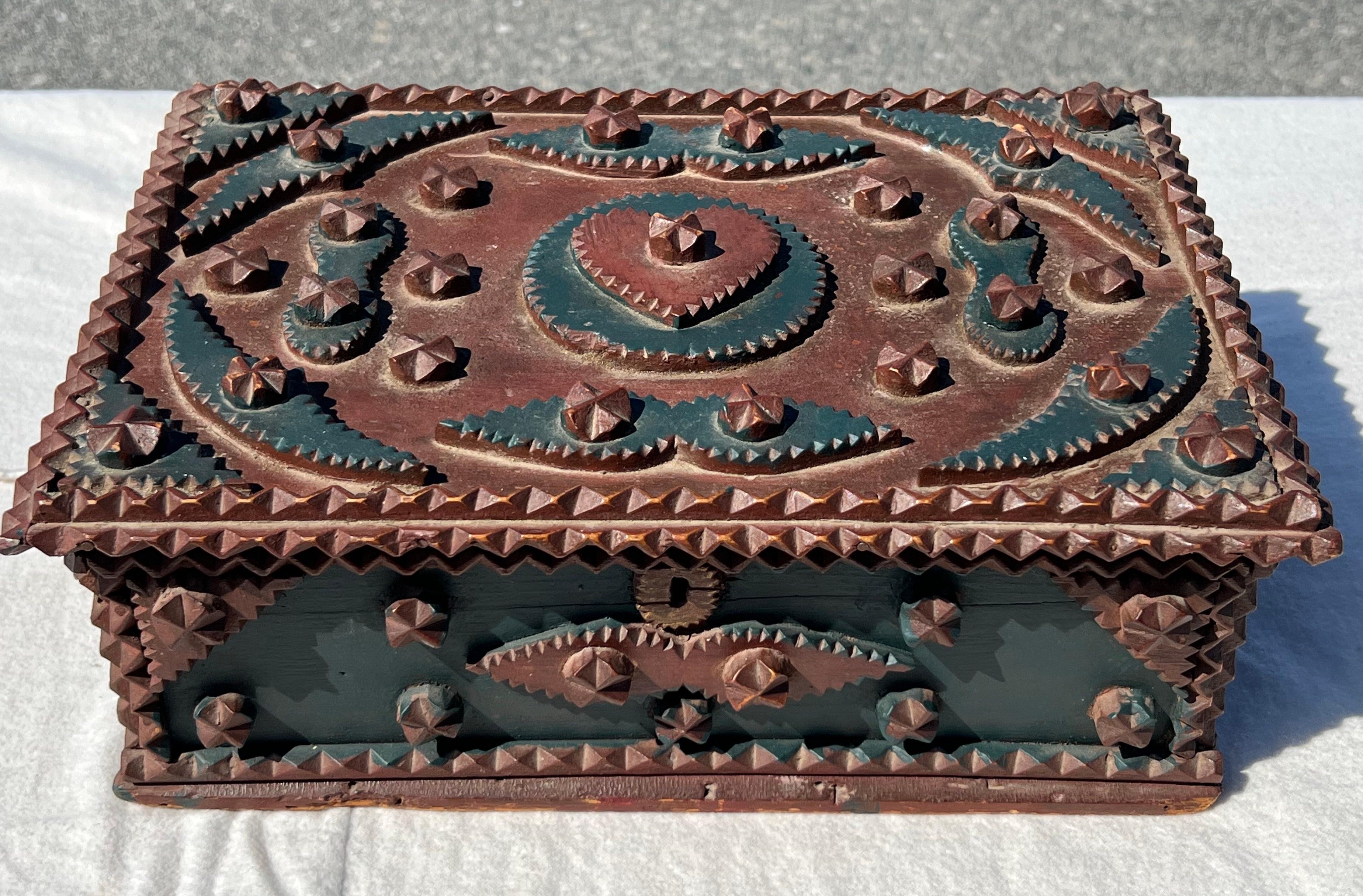 tramp-Art-Kasten aus dem 19. Jahrhundert mit aufklappbarem Deckel. Angewandte Schnitzereien, darunter Herzen und Rosetten, mit blauer und roter Außenbemalung und einem doppelten Rahmen mit Schnitzereien auf dem Innendeckel. Alter