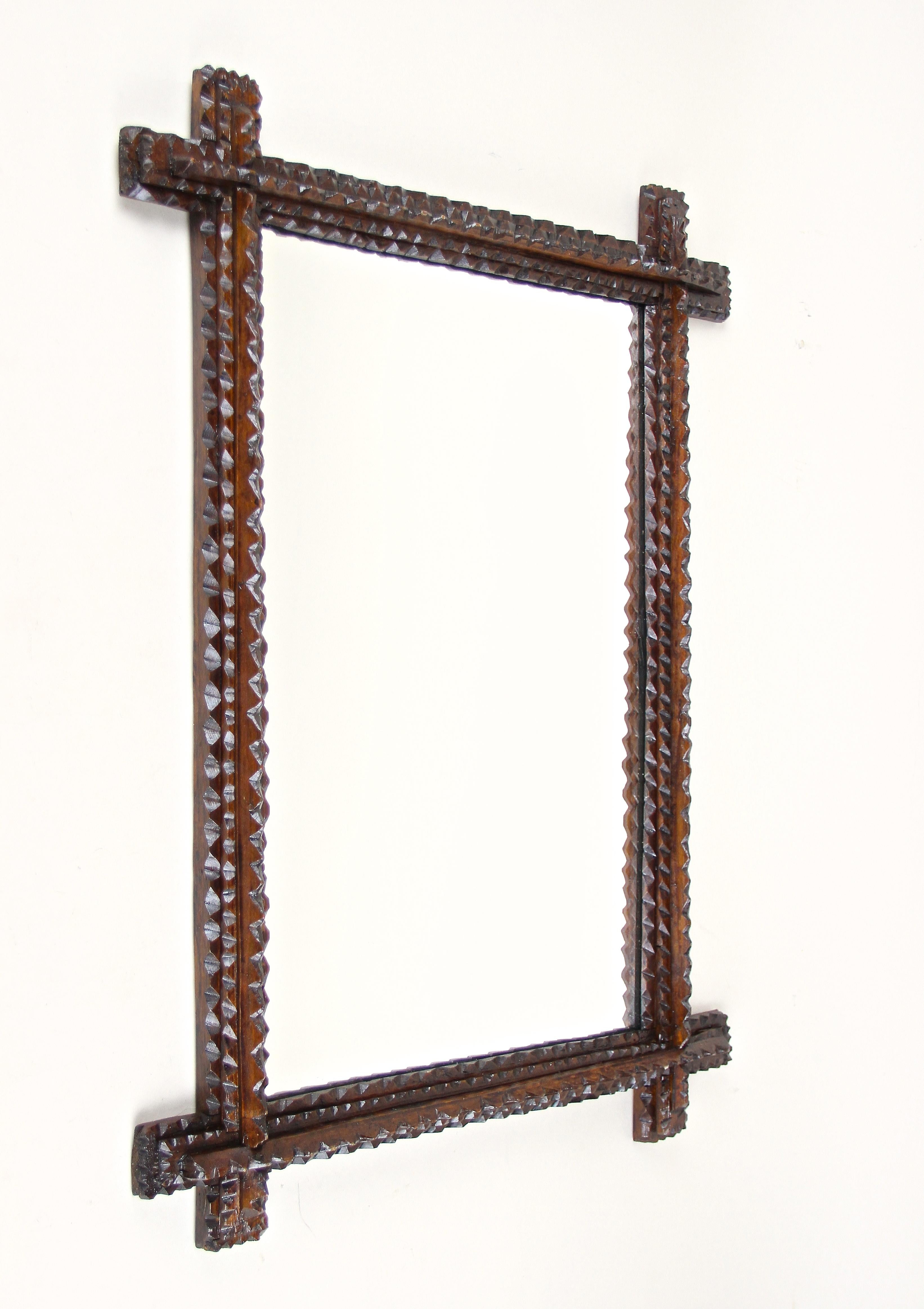 Exceptional looking rustic 19th century Tramp Art mirror out of Austria. This fantastic rustic wall mirror from around 1870 convinces by its great variety of chip carvings. Slightly protruding corners and the dark brown stained frame makes this
