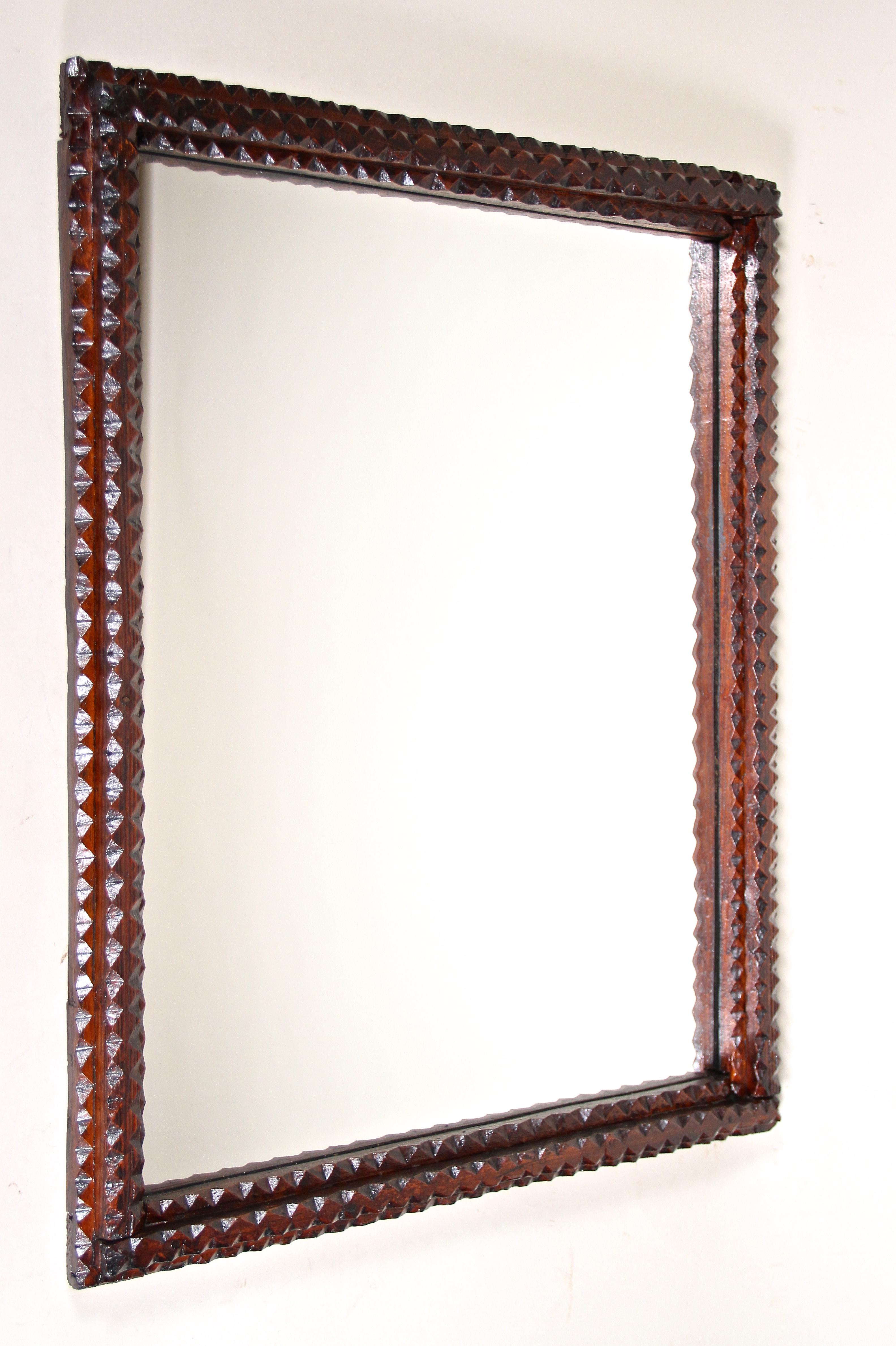 Lovely late 19th century rustic Tramp Art mirror out of Austria from around 1880. The darkbrown stained, hand carved basswood frame shows beautiful chip carvings - a technique which confers this very popular kind of mirrors this special rural touch.