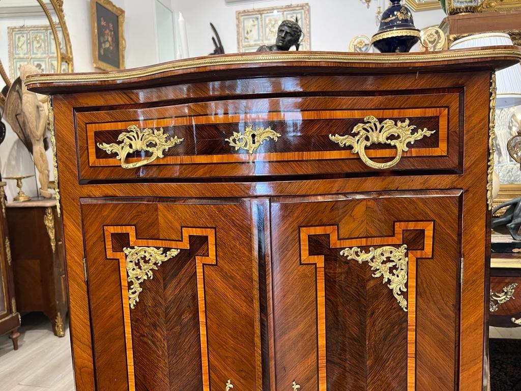 A transition-style buffet d'entre deux from the Napoleon III era. It has a curved front and opens with two doors on the sides and a large drawer above them. The marquetry is adorned with a maze-like design, also known as the Greek key motif, in