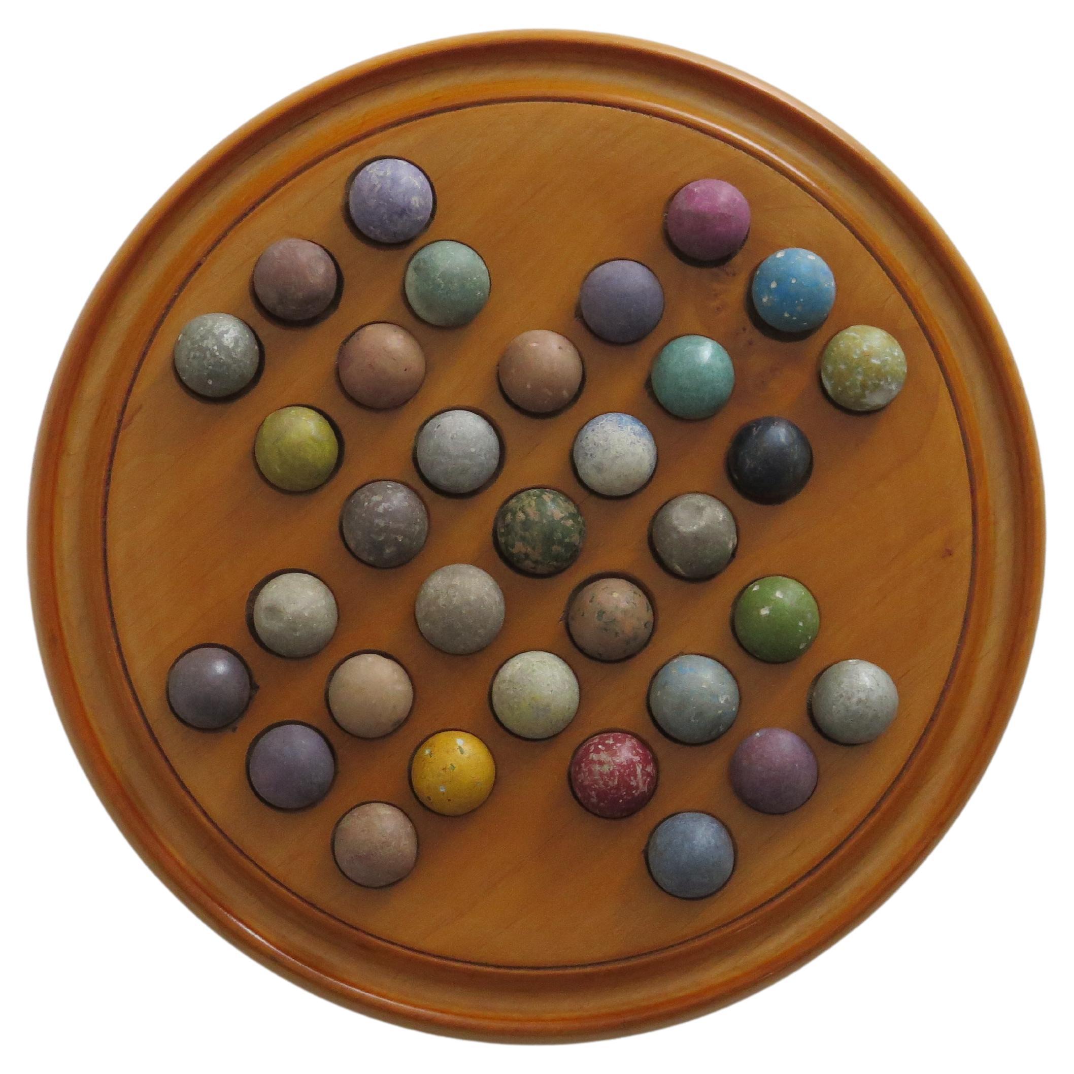 This is an original and complete game of travelling marble solitaire from the 19th century with 33 old clay and stone marbles, circa 1870.

This very good two-piece board has a circular open wood base storage section, which is screwed to the