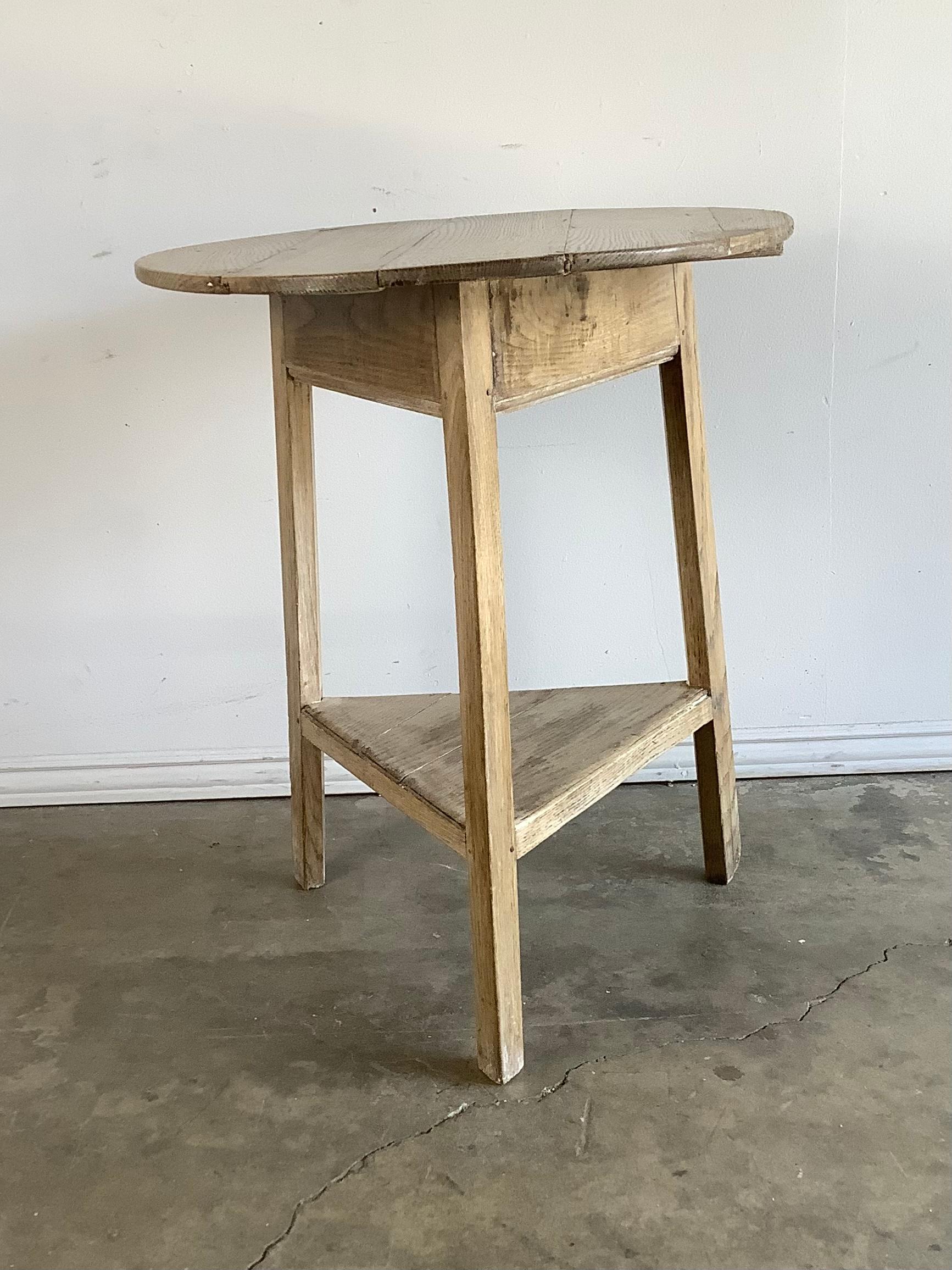 Charming 19th c. two-tiered white washed Oak Cricket table. The tripod table stands on three legs that connect to a center triangular shelf. It is the perfect accent table for any location.