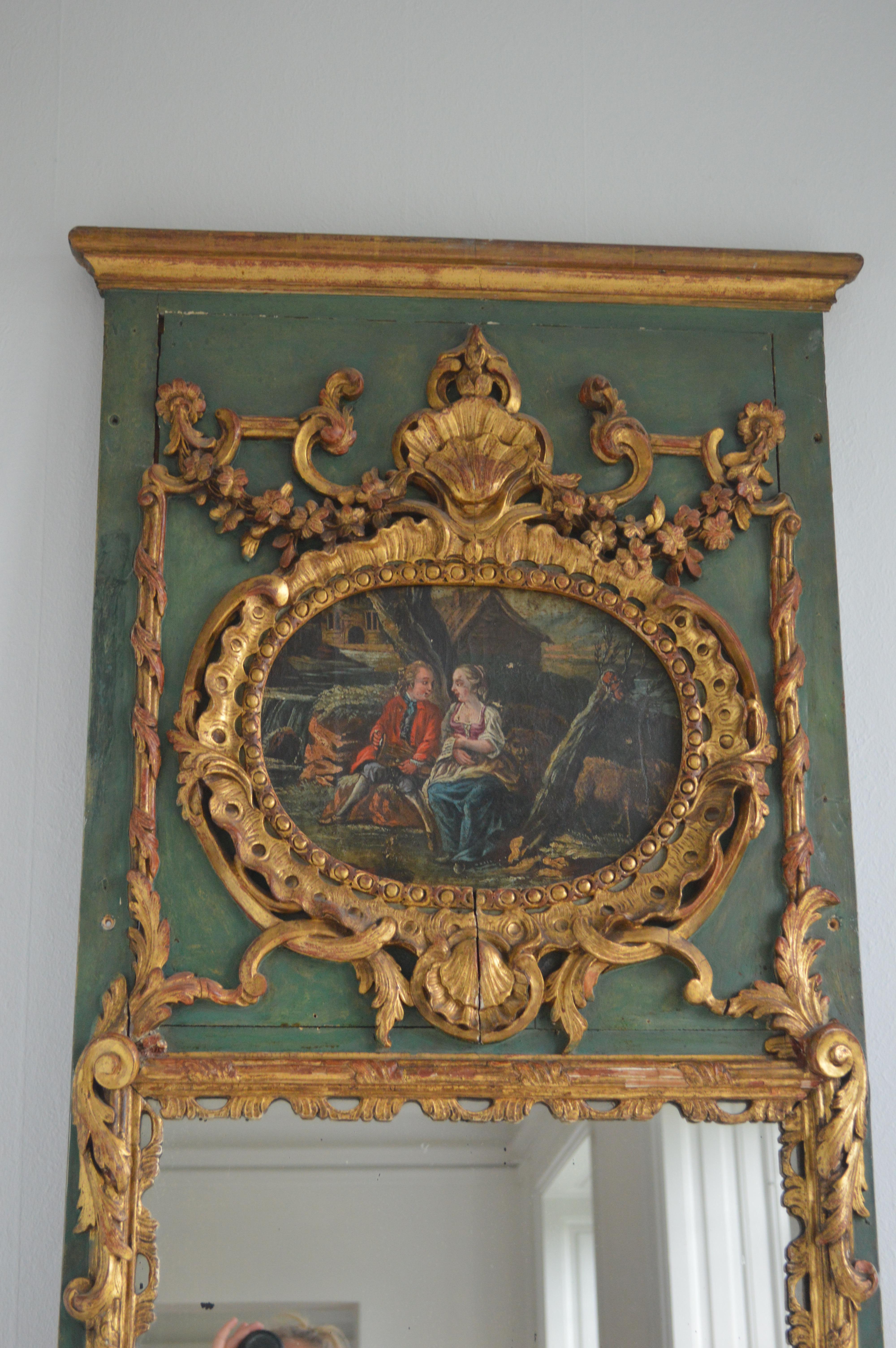 19th century trumeau gilded Rococo, original mercury mirror. Richly carved green painted with a romantic landscape scenery.
 