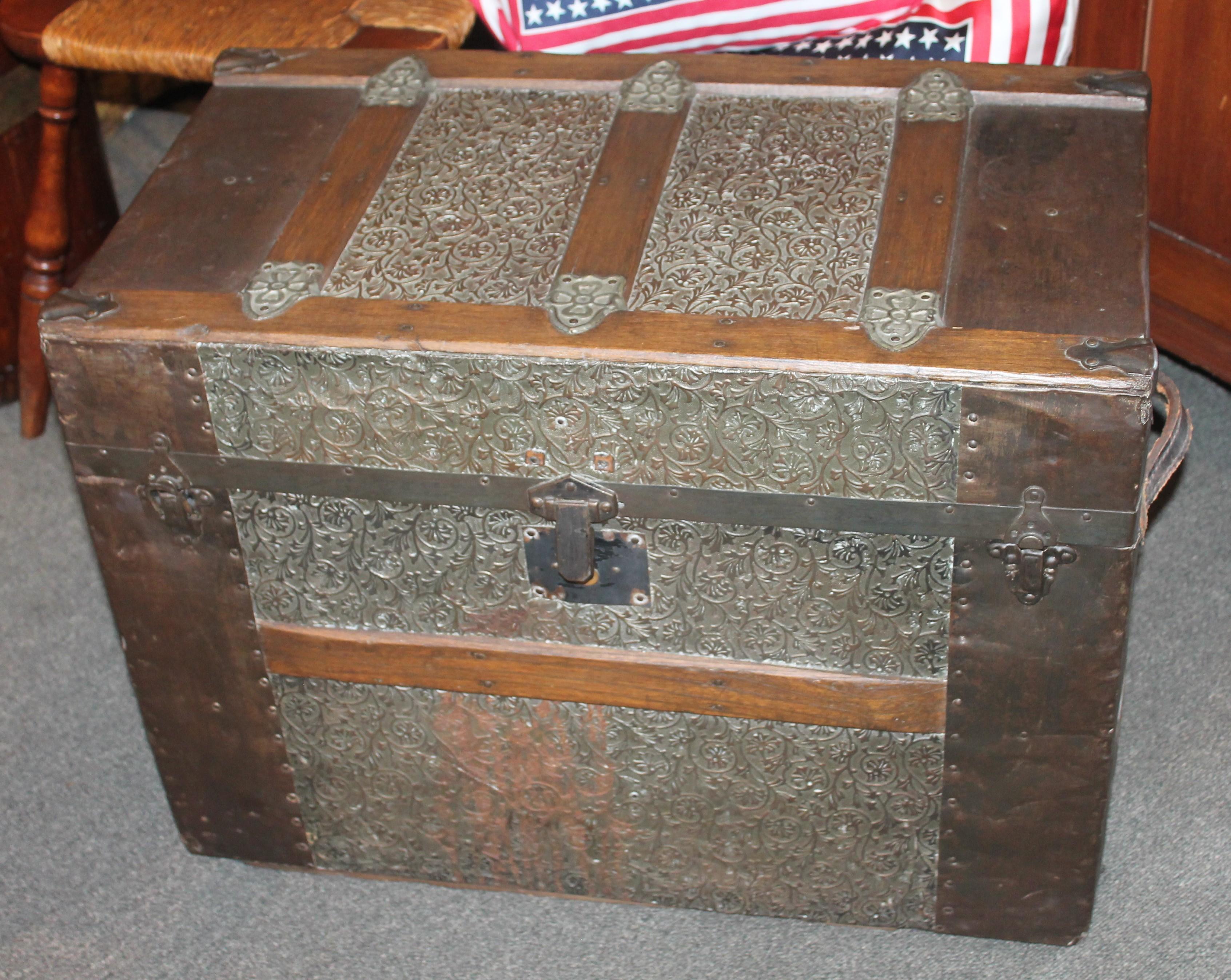 This 19th century wood trim trunk is in fine condition and has the original leather handles. The tin and metal trim is all in good condition. The inside liner is newly wall paper lining. This trunk has the original metal wheels.