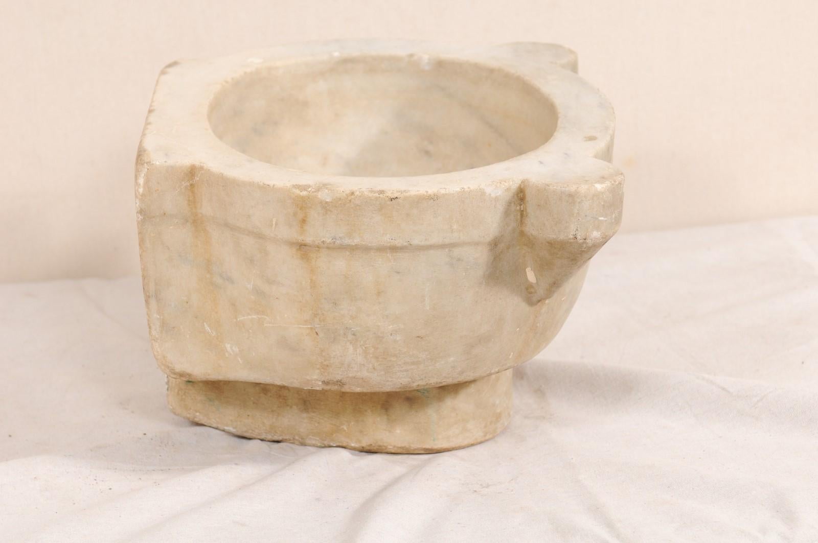 A smaller-sized Turkish hammam wash basin of marble from the 19th century. This antique hand-carved marble basin was once used within a Turkish bath house, or hammam. The backside of the basin remains flat, allowing it to be placed flush against a