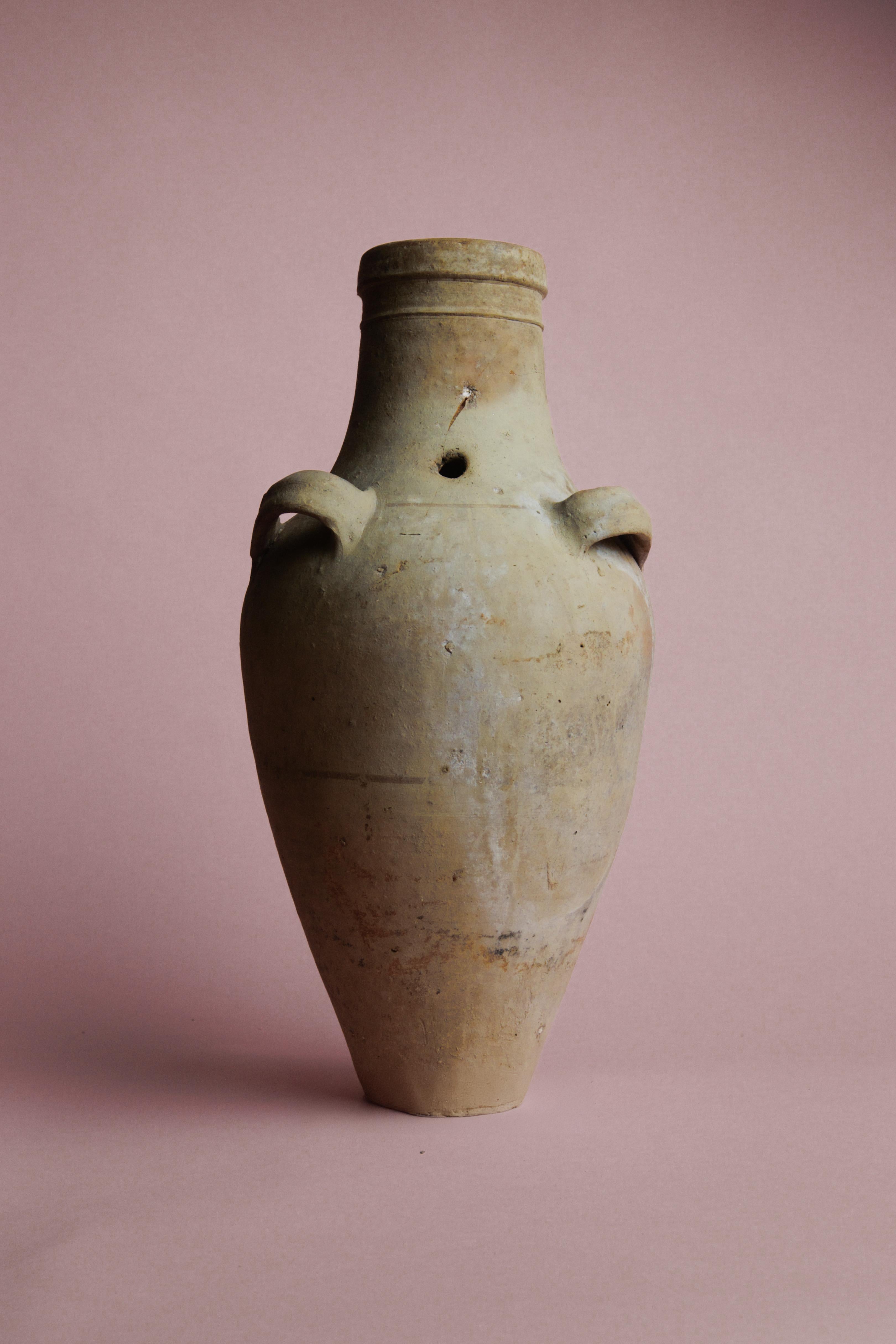 Questo vaso da olio turco del XX secolo è un bellissimo esempio di ceramica mediterranea d'epoca, un tempo utilizzata per conservare l'olio d'oliva. Realizzato a mano con la cura del tempo, questo vaso, che funge anche da vaso, presenta una patina