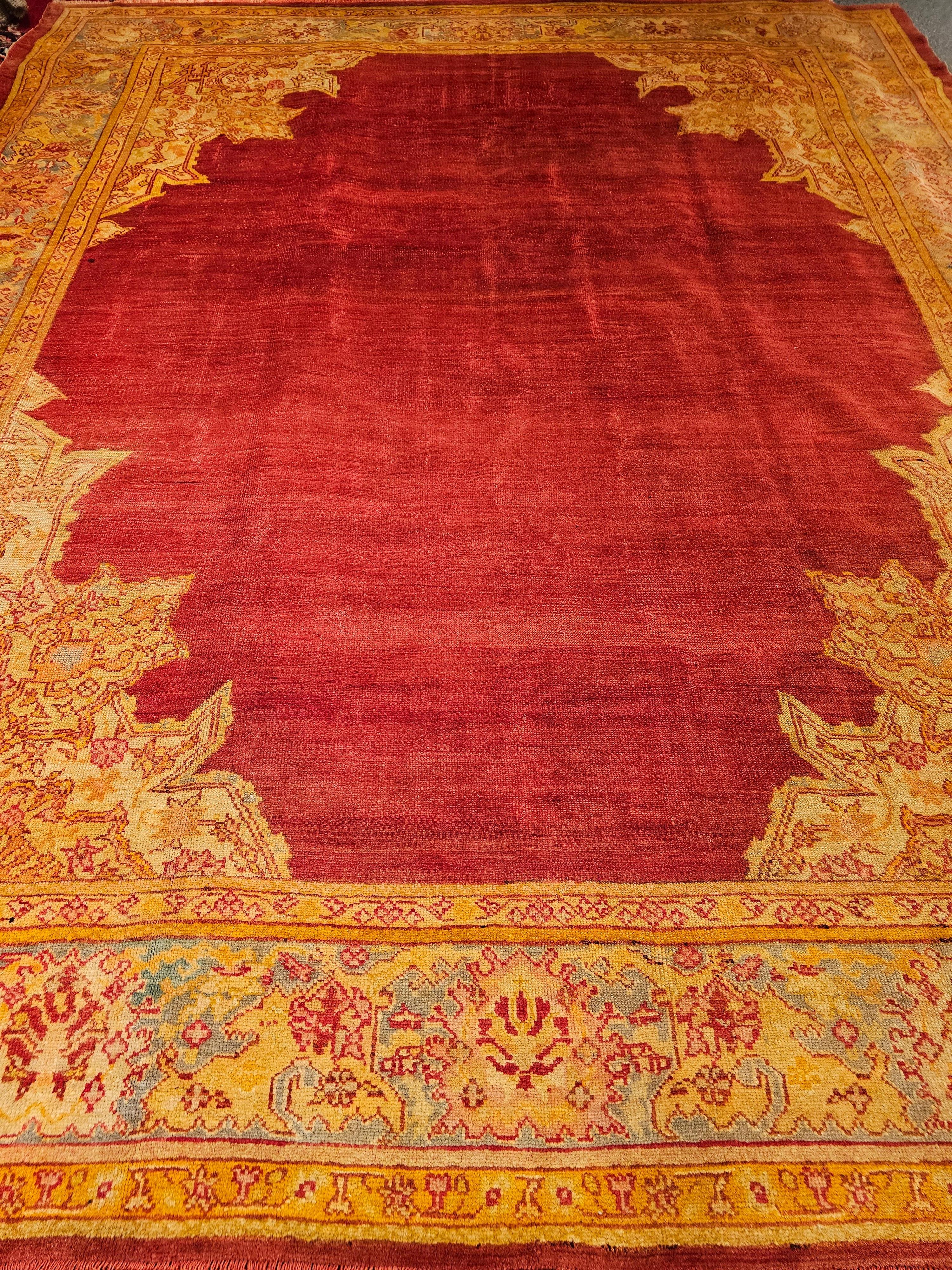 Late 19th Century Turkish Oushak room size rug in an open field pattern in brilliant colors of red, turquoise, and yellow.  The center of this beautiful Oushak is completely open and is in red.  The corner spandrels have palmate and arabesque design