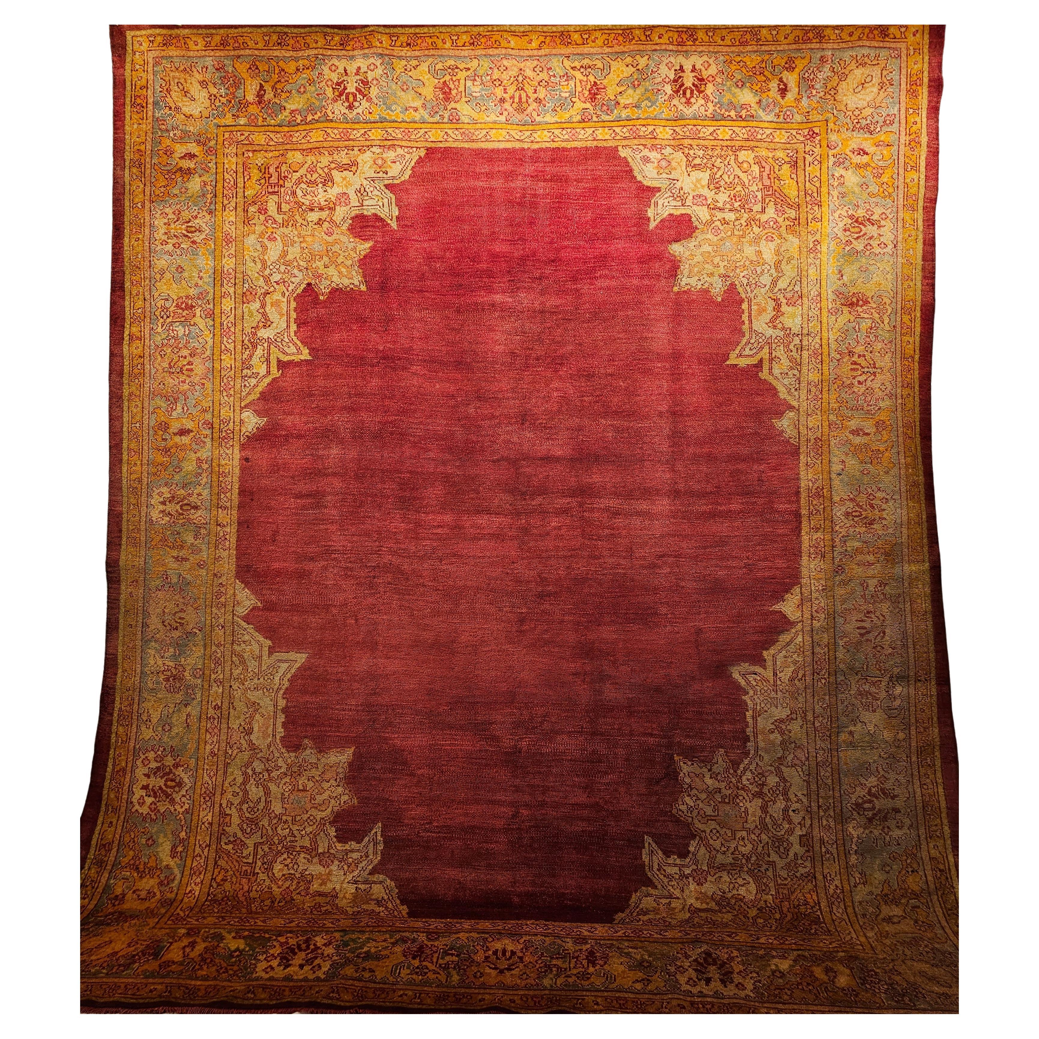 A late 19th Century Turkish Oushak room size rug in an open field design in brilliant colors of red, turquoise, and yellow.  The center of this beautiful Oushak is completely open and is in red.  The corner spandrels have palmate and arabesque