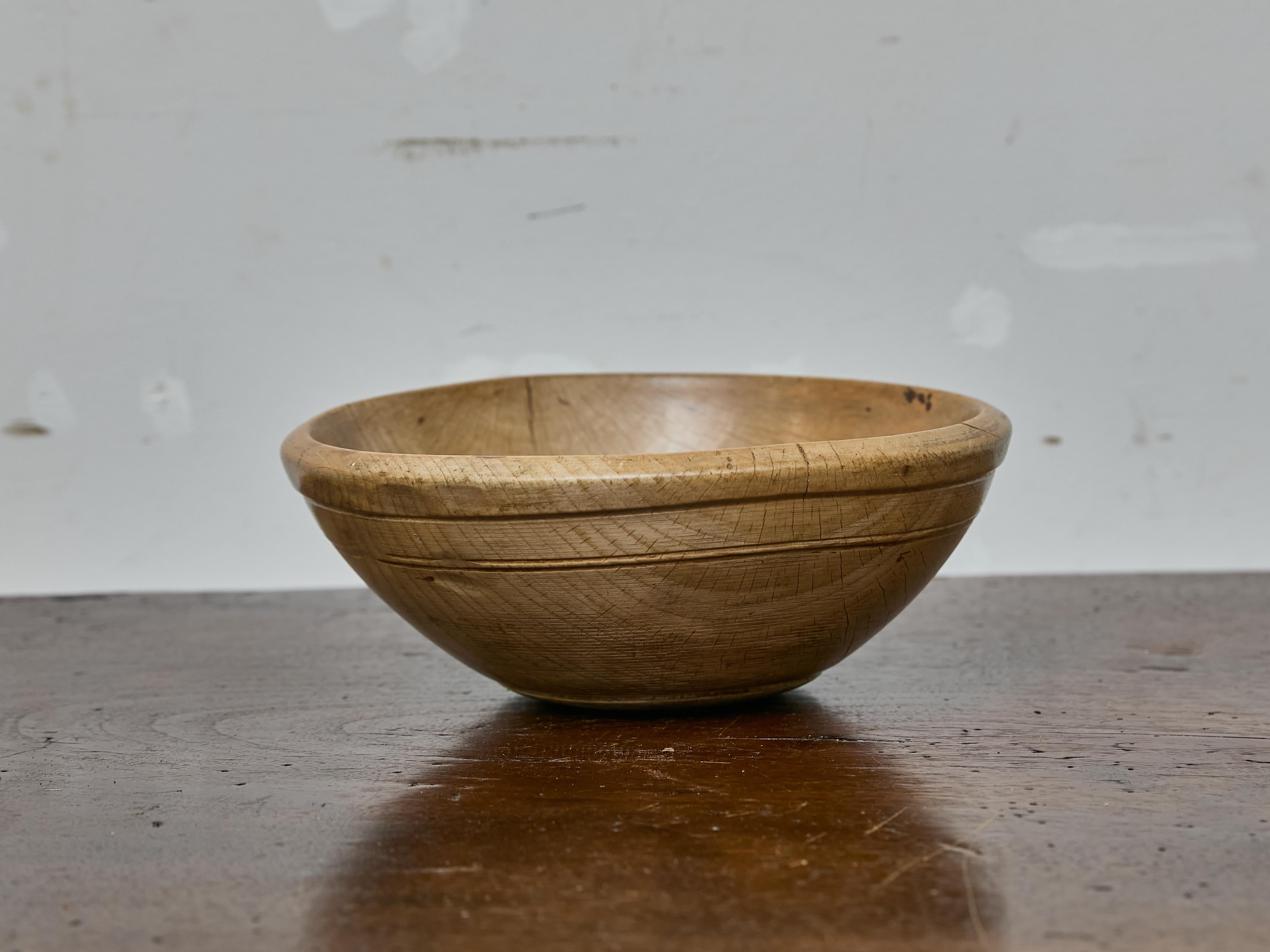 This 19th-century birchwood bowl is a beautifully aged example of early domestic craftsmanship, turned from a single piece of wood and marked by generations of use. Measuring 12.25 inches across and 5 inches high, the bowl features a slightly