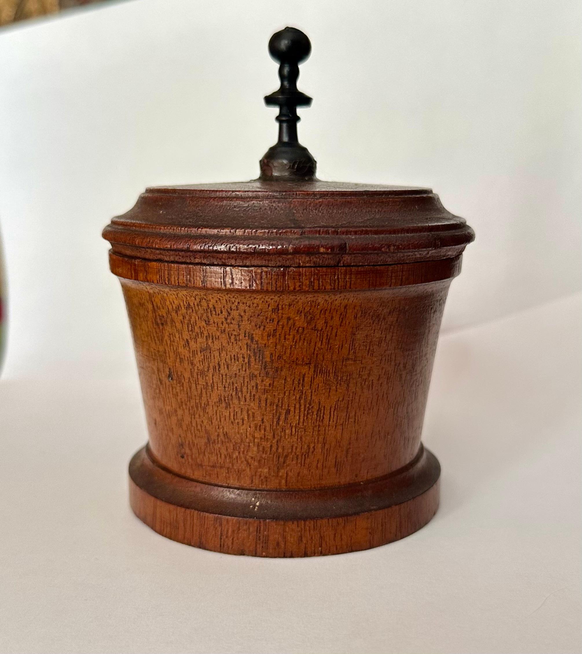 19th Century Turned Wood Tobacco Jar. 

Attractive and skillfully made 19th Century turned Lignum Vitae tobacco pot with lid. The treen with fitted, turned lid has a center raised finial handle. The stepped lid is over a cylindrical ring turned body