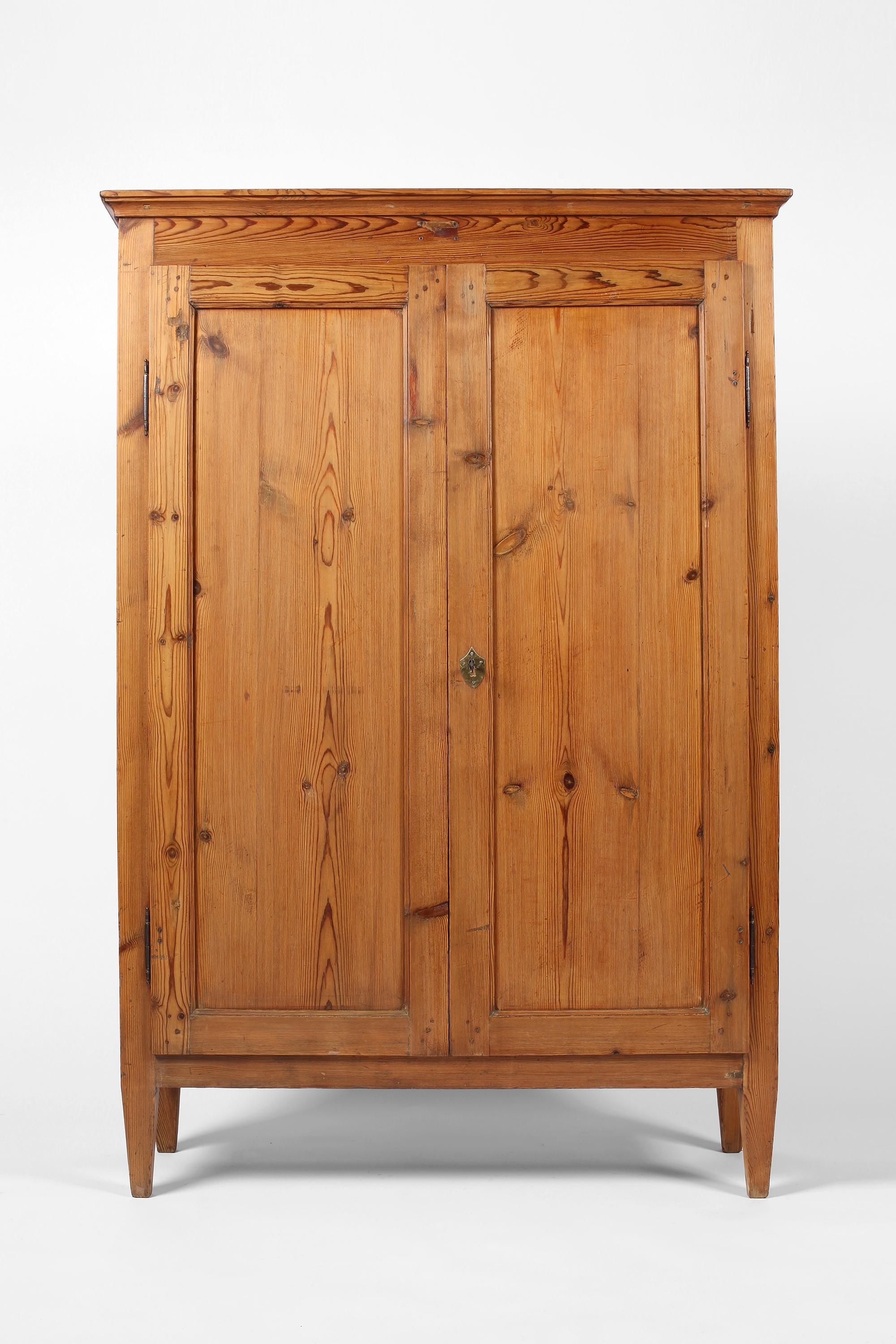 A charming early 19th century two door pine cupboard from Tuscany. Simple in form and sitting on four tapered feet, the two doors open to reveal three shelves within. With working original lock and key. Italian, c. 1800.