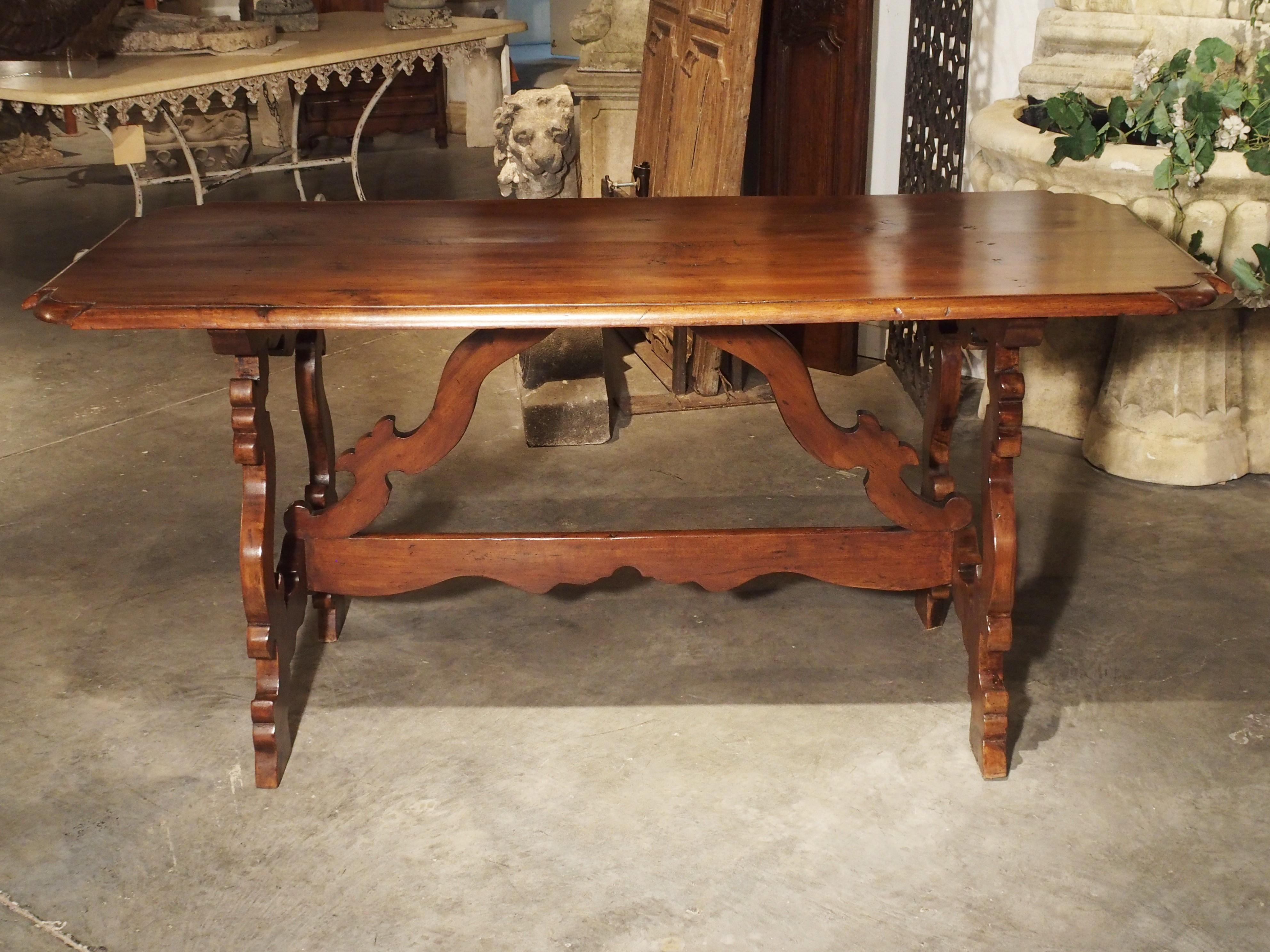 Datant du XIXe siècle, cette table toscane présente un plateau aux coins arqués et un magnifique châssis en bois façonné. Les pieds sont ornés de volutes en forme de C et de S et d'un châssis double, l'un horizontal et les deux autres arqués vers le