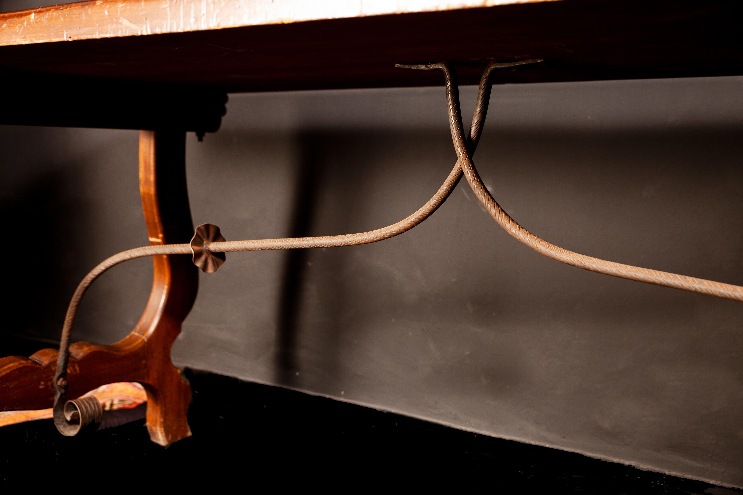 A Tuscany walnut table with rectangular top and sophisticated lyre legs, joined by wrought iron stretcher.