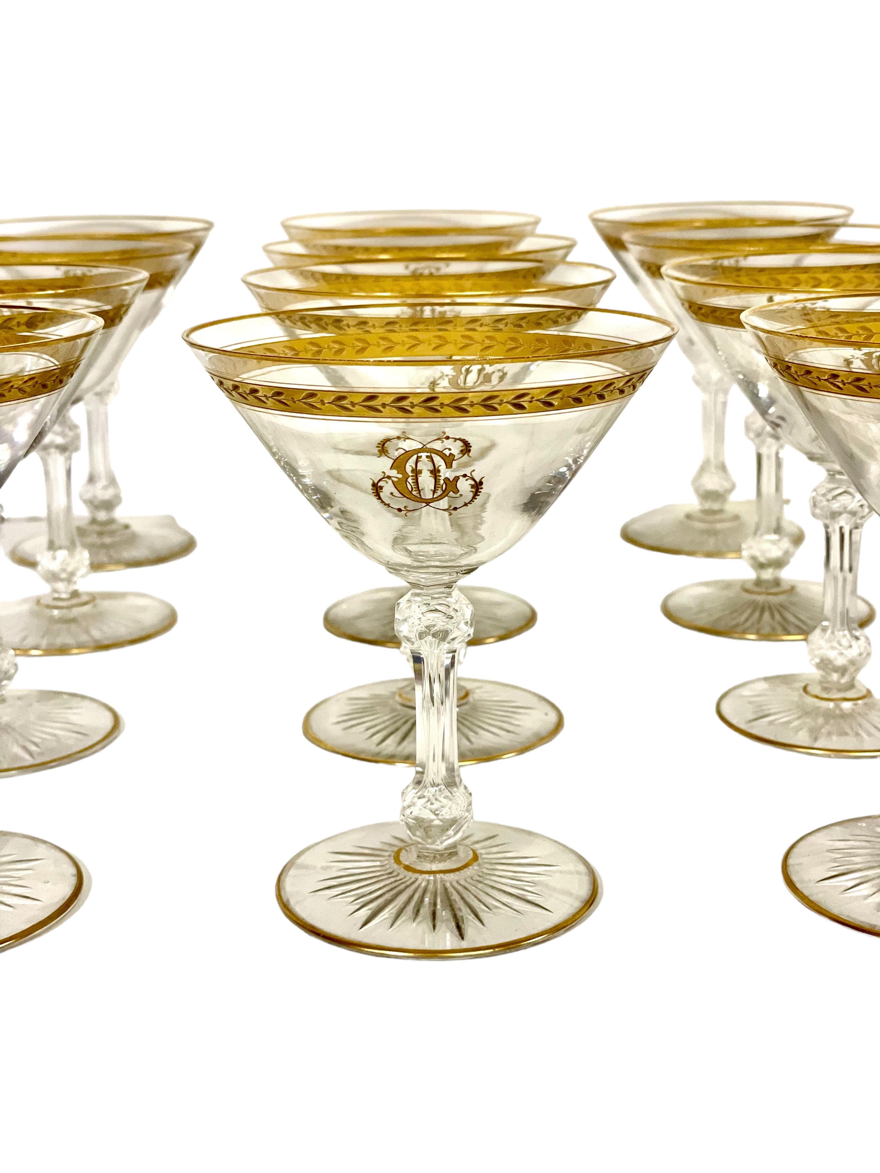Un elegante set di dodici bicchieri da champagne in cristallo del XIX secolo, ognuno dei quali è generosamente impreziosito da un bordo dorato e da una fascia superiore di foglie d'alloro dorate e presenta un elaborato monogramma 