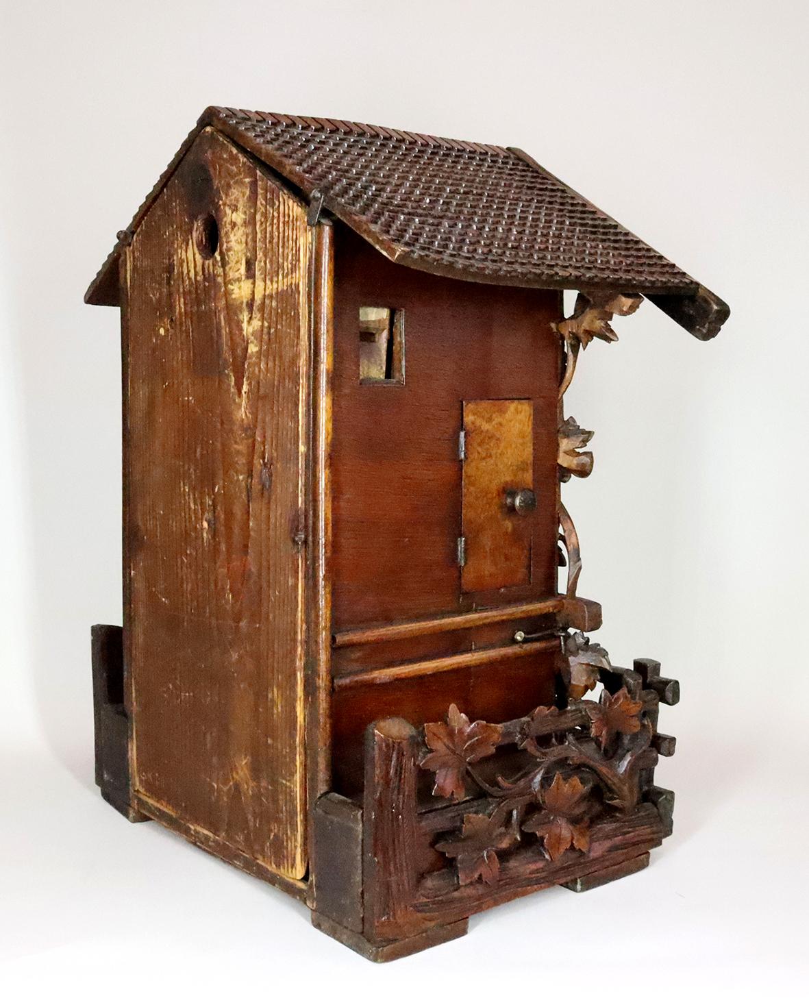 This Black Forest cuckoo clock has a twin fusee movement complete with typical wooden plates and original bellows and pendulum. The case is made in the highest tradition of black forest wood carving, with intricately hand carved roof shingles and