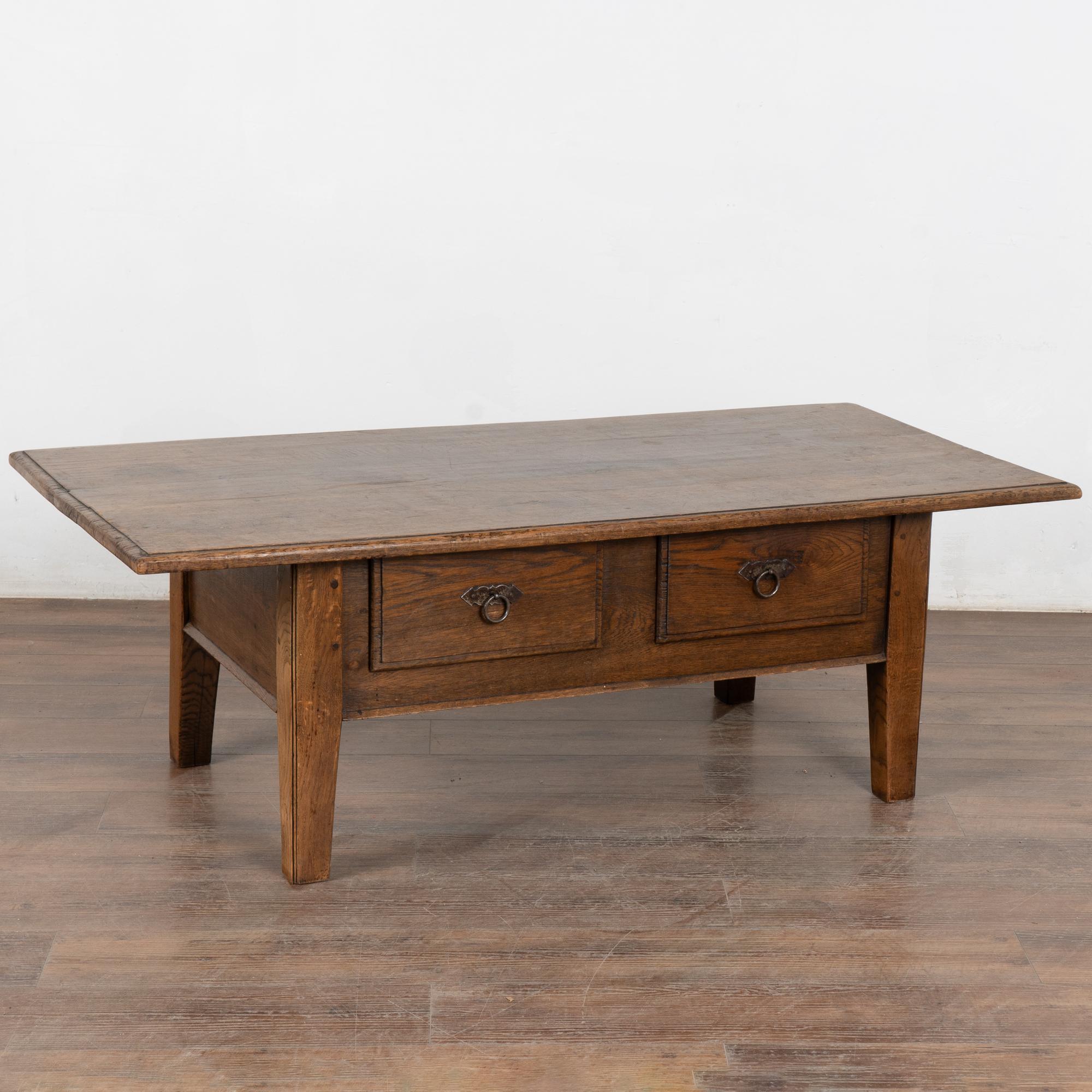 L'attrait rustique de cette table basse en chêne provient de la patine vieillie du bois usé.
Chaque égratignure, entaille, fissure, gouge et tache ne fait qu'ajouter à l'attrait de cette table basse de style français avec deux tiroirs.
Restauré,