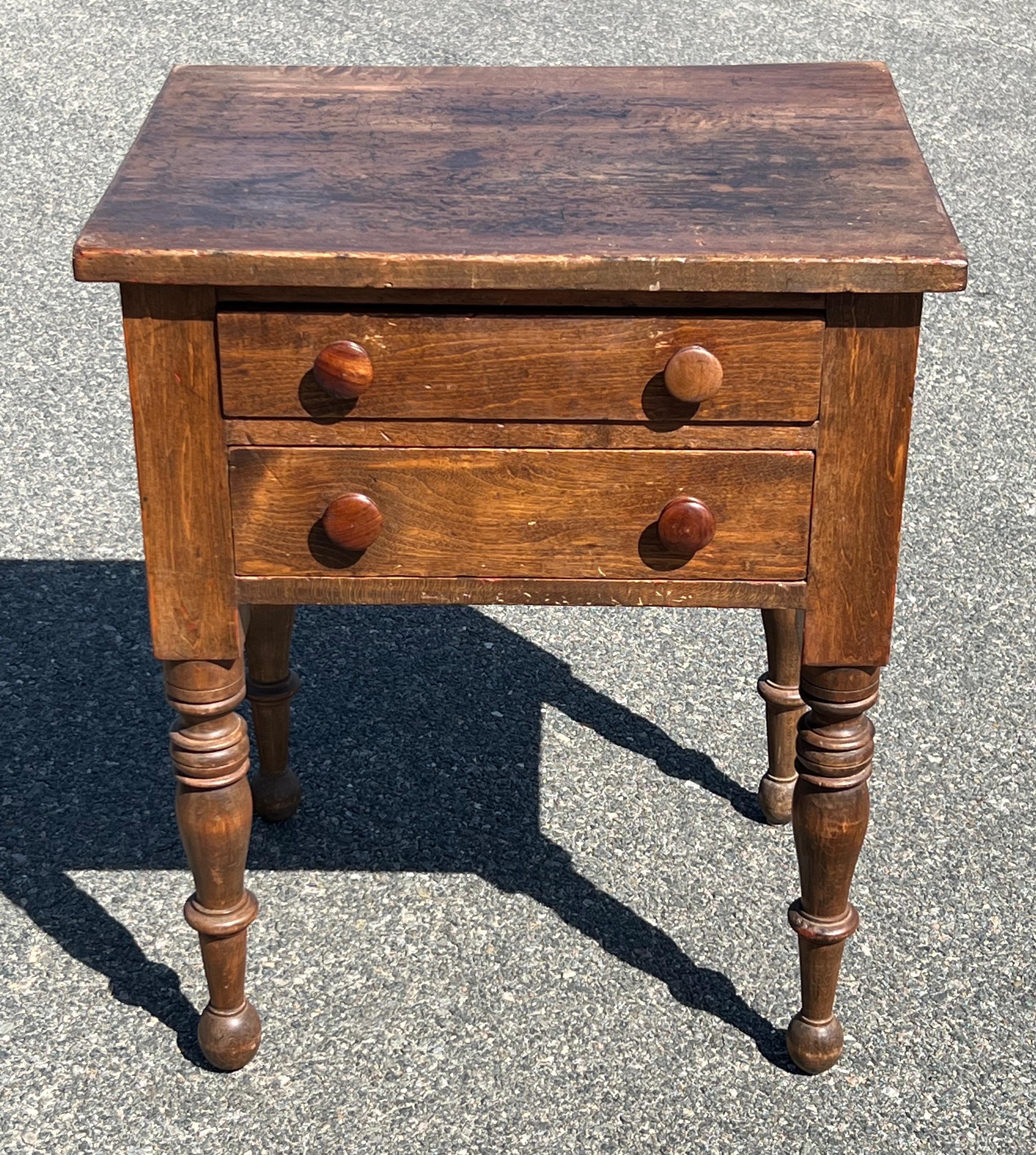19th century two drawer stand, maple construction with some tiger grain visible.  Original yellow painted drawer interiors, knobs likely replaced, boldly turned legs and bun feet.